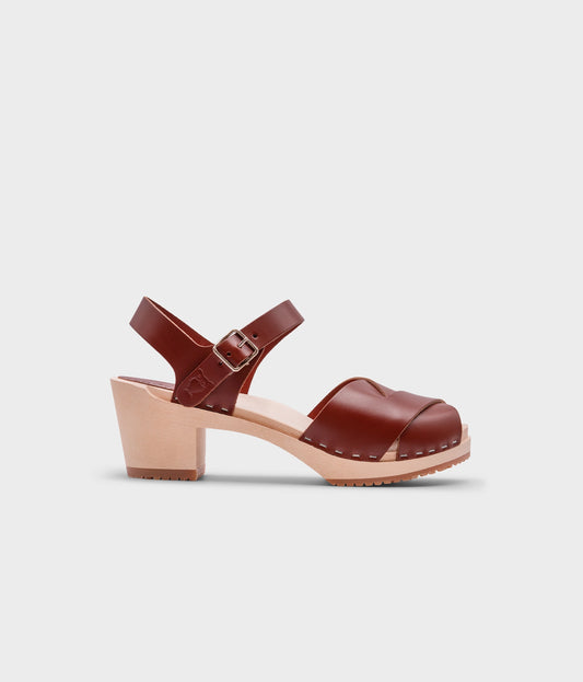 high heeled clog sandals in cognac red vegetable tanned leather with an open-toe stapled on a light wooden base