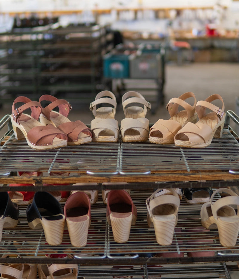 high rise heel crossed clog sandals in blush pink nubuck leather stapled on a light wooden base