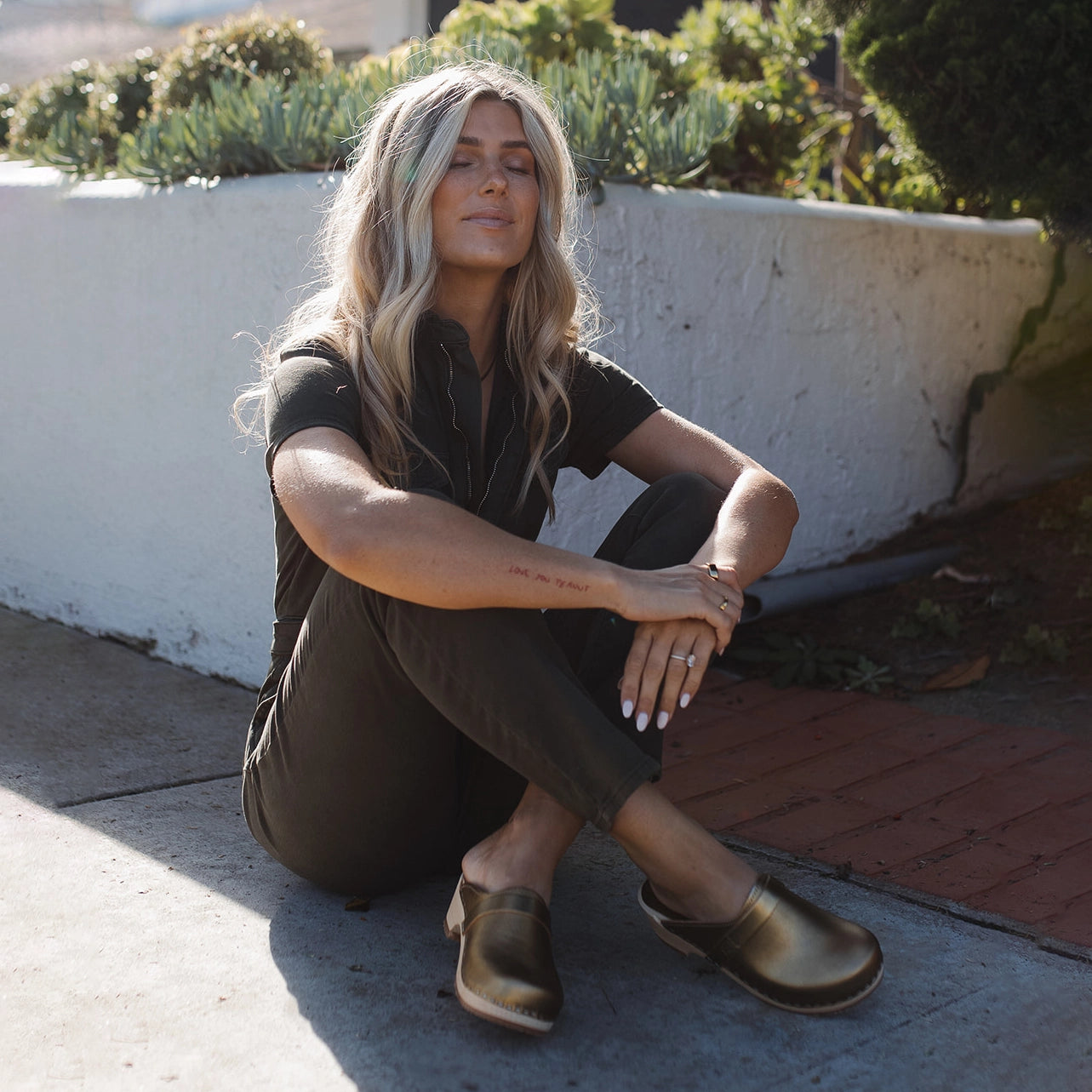 Blond women sitting down with a pair of Sandgrens Tokyo in Gold Metallic