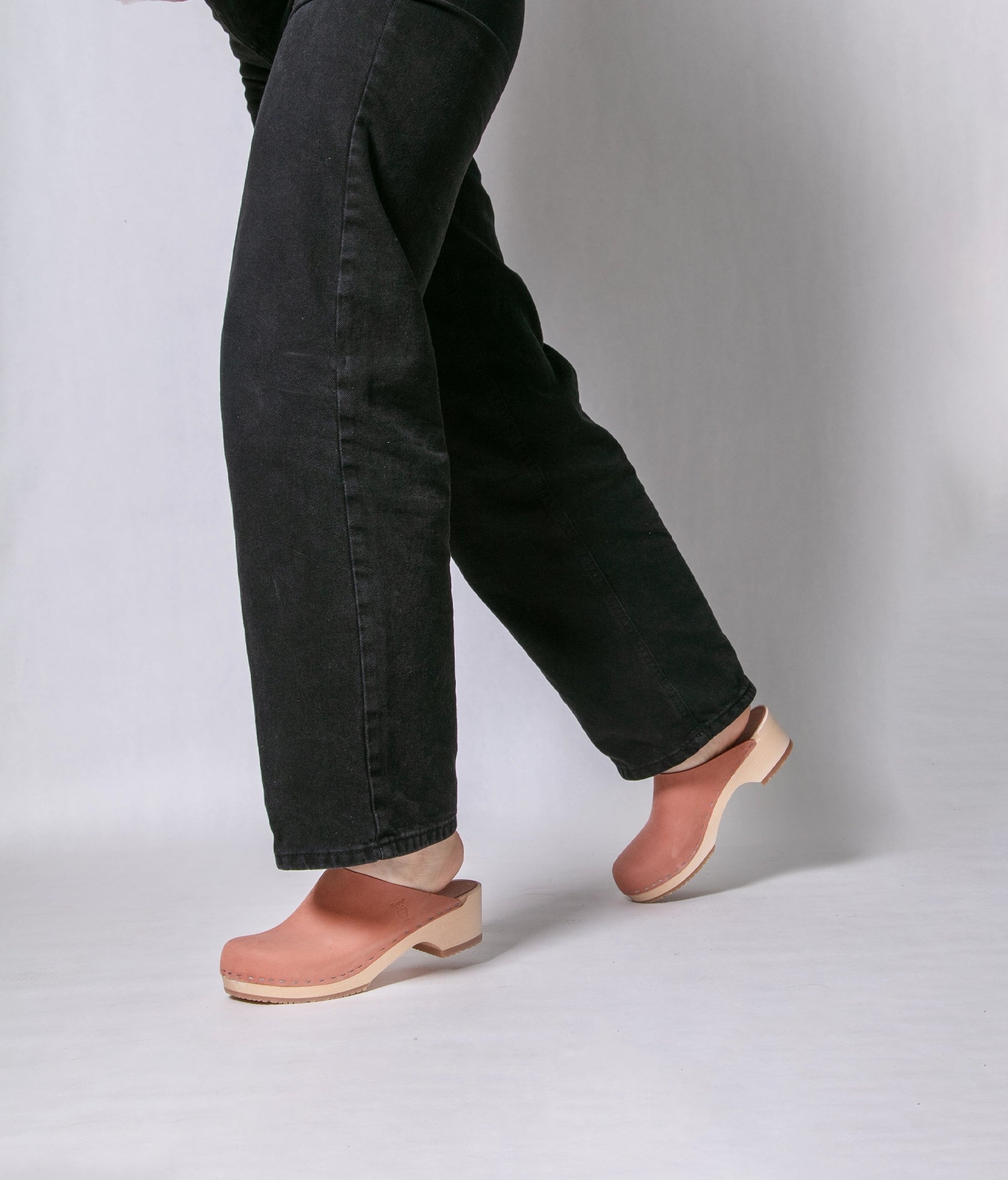 low heeled minimalistic clog mules in blush pink nubuck leather stapled on a light wooden base