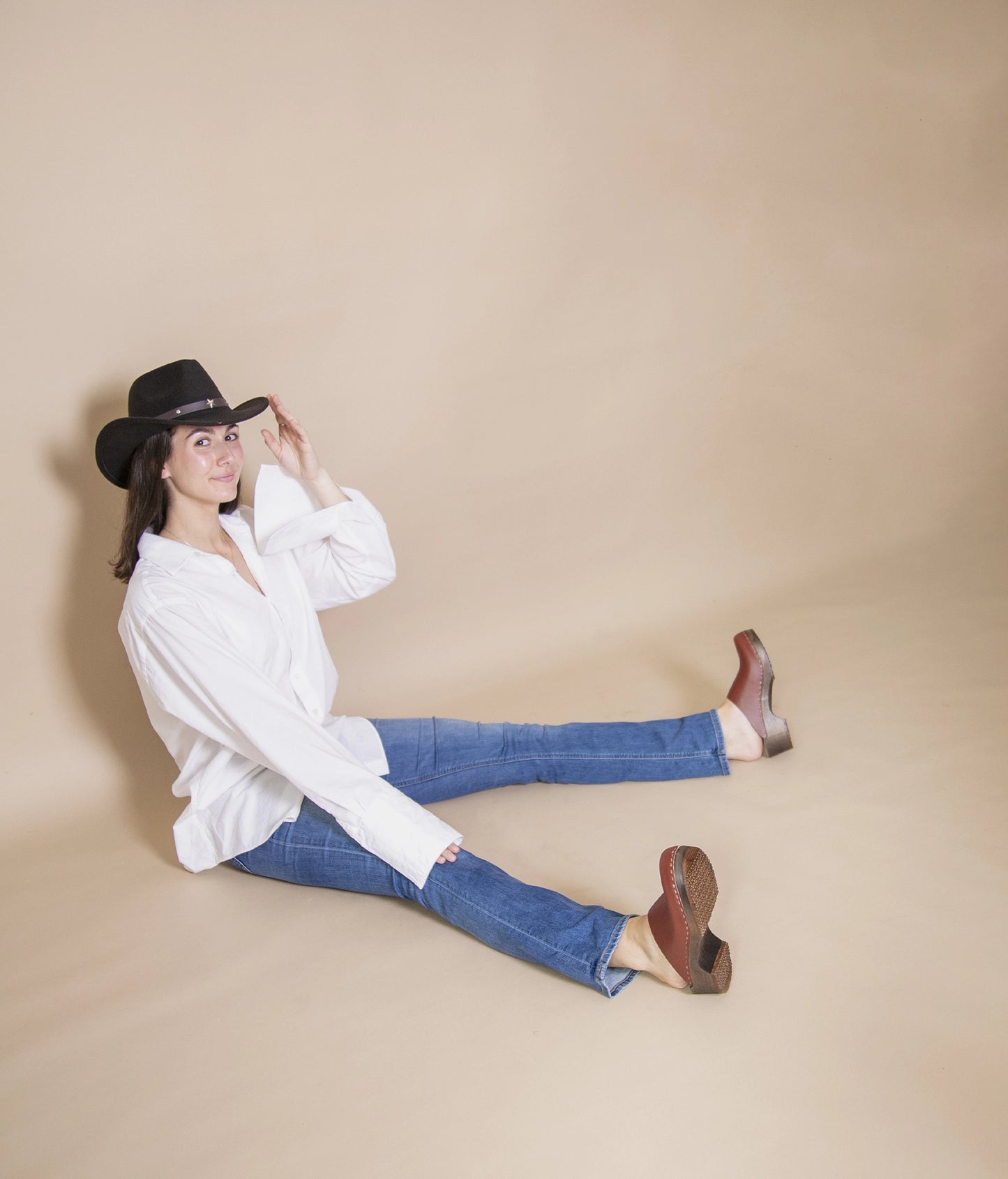 low heeled minimalistic clog mules in cognac vegetable tanned leather stapled on a dark wooden base