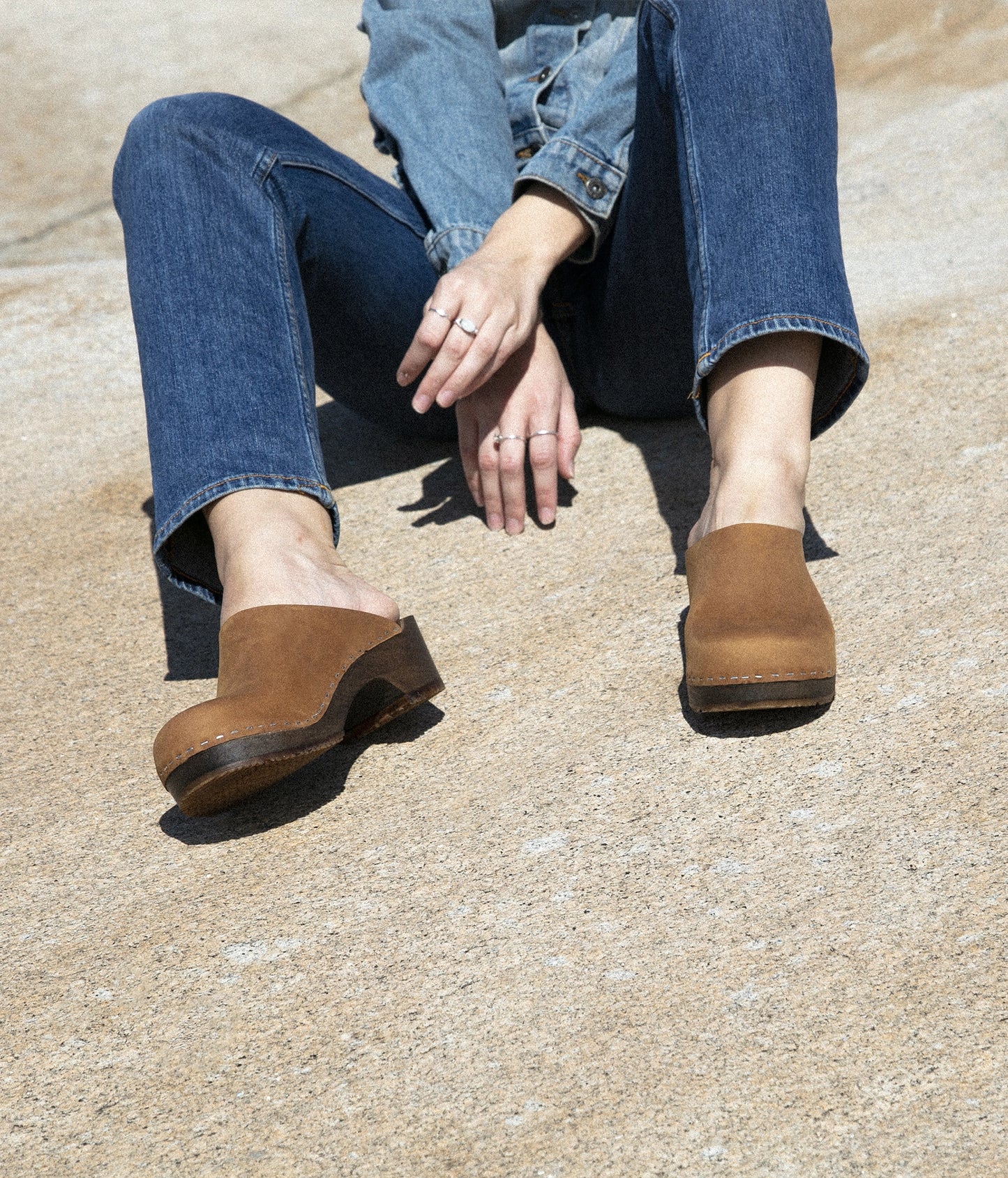 low heeled minimalistic clog mules in dexter tan nubuck leather stapled on a dark wooden base