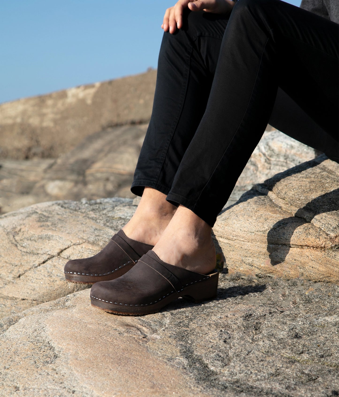 low heeled classic clog mules in dark brown nubuck leather stapled on a dark wooden base