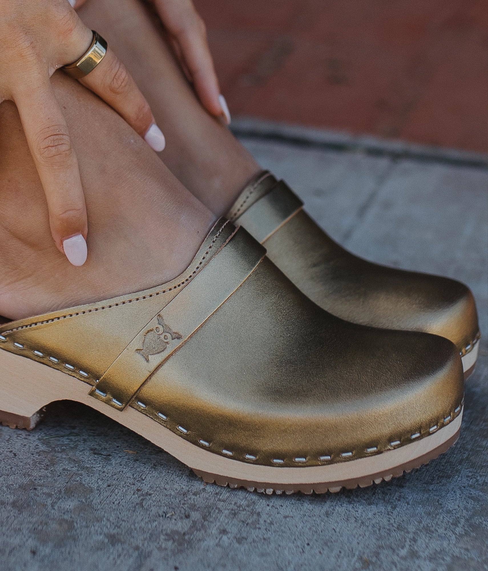 classic low heeled clog mule in rustic gold vegetable tanned leather stapled on a light wooden base with a leather strap