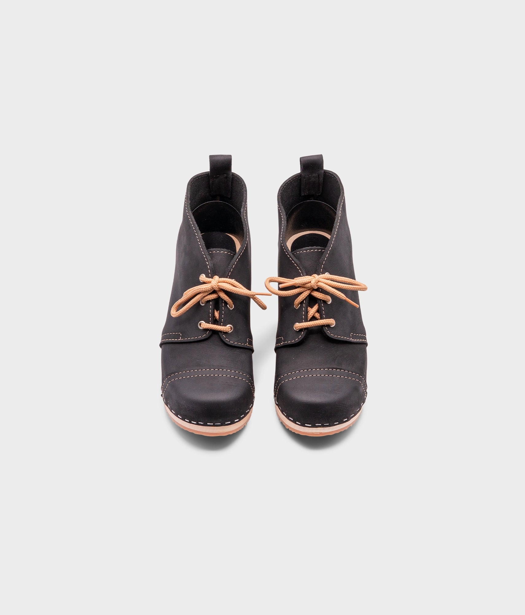 high heeled chukka clog boots in black nubuck leather stapled on a light wooden base with beige laces