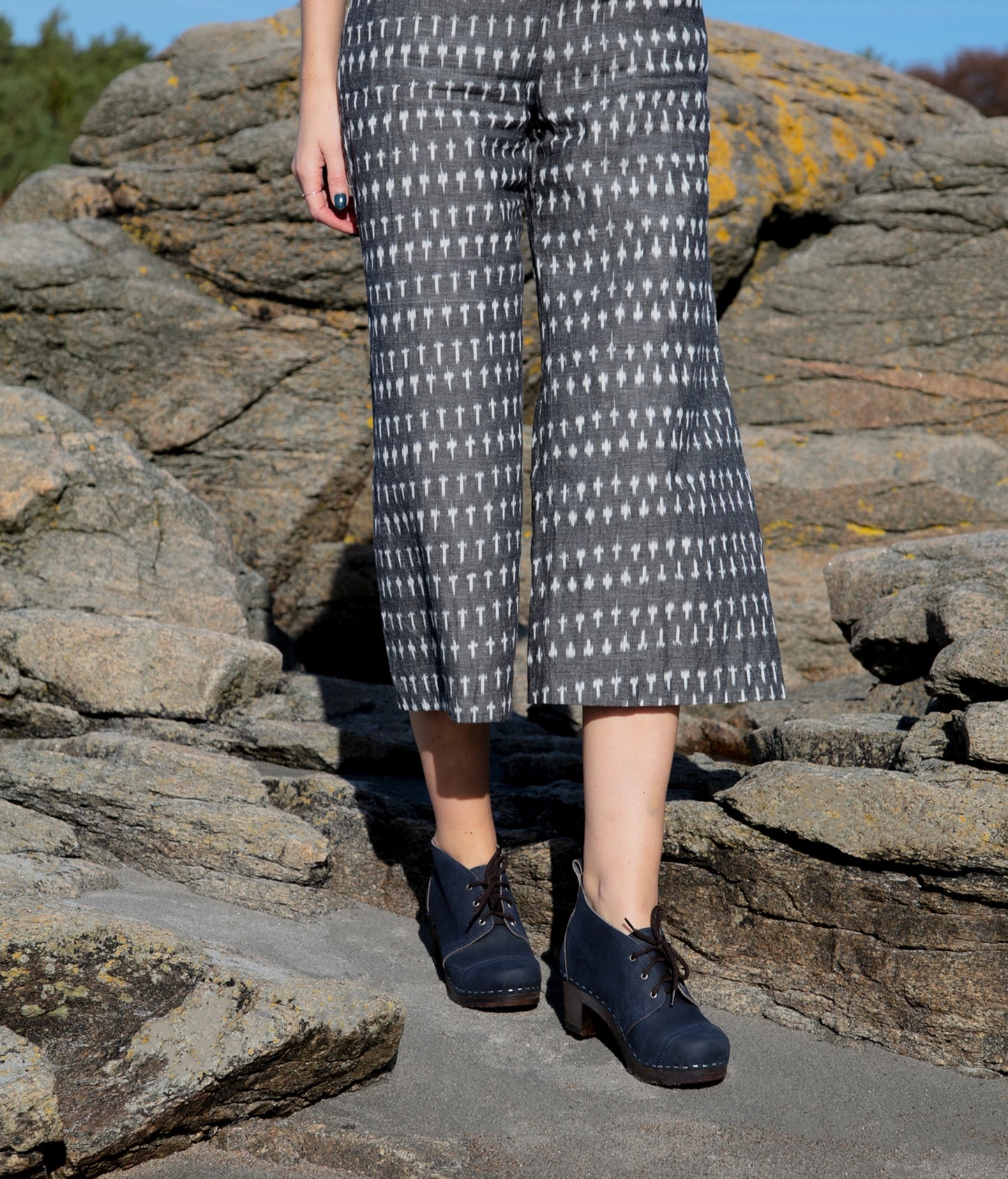 high heeled chukka clog boots in navy blue nubuck leather stapled on a dark wooden base with brown laces