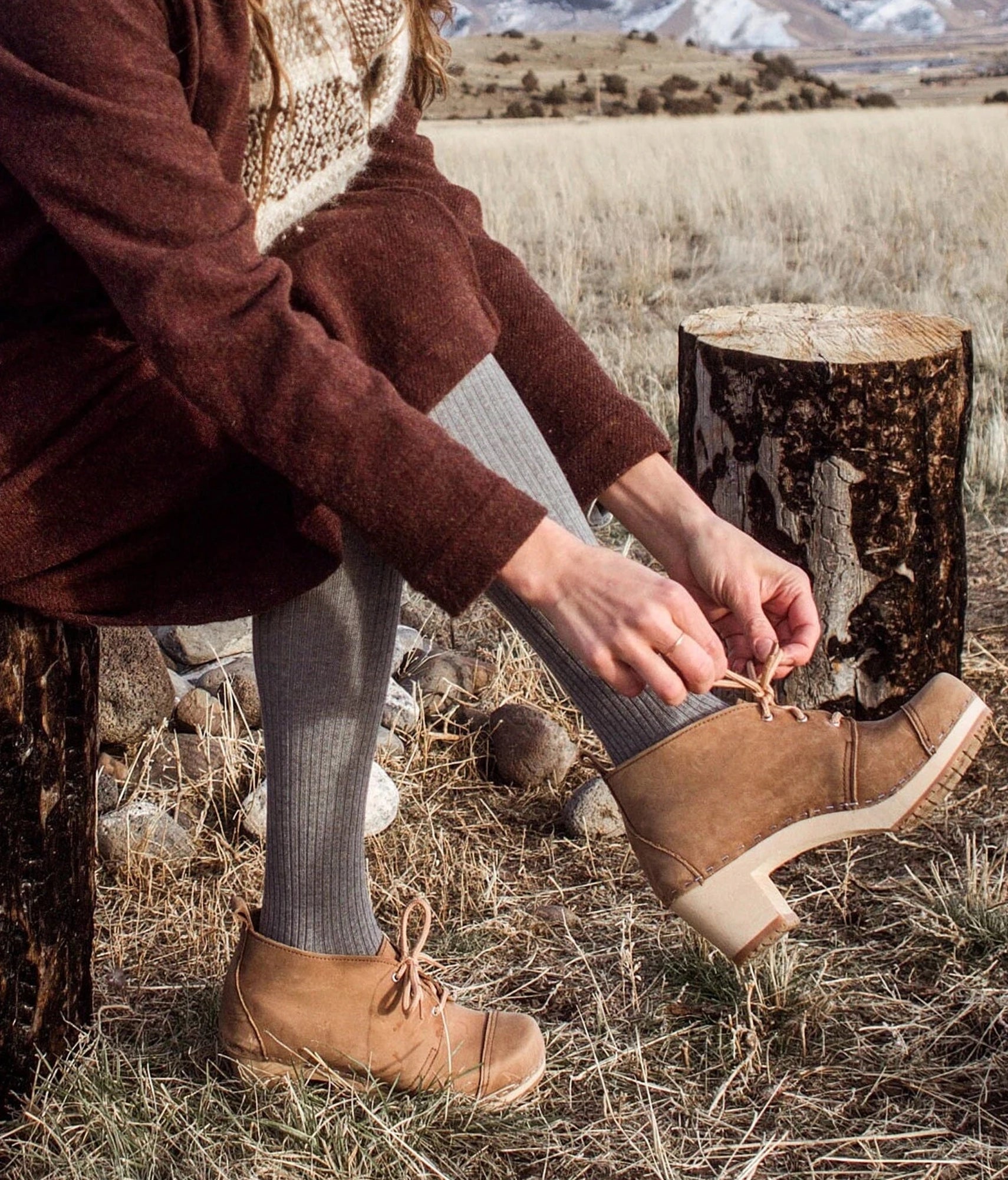 high heeled chukka clog boots in navy blue nubuck leather stapled on a dark wooden base with brown laces