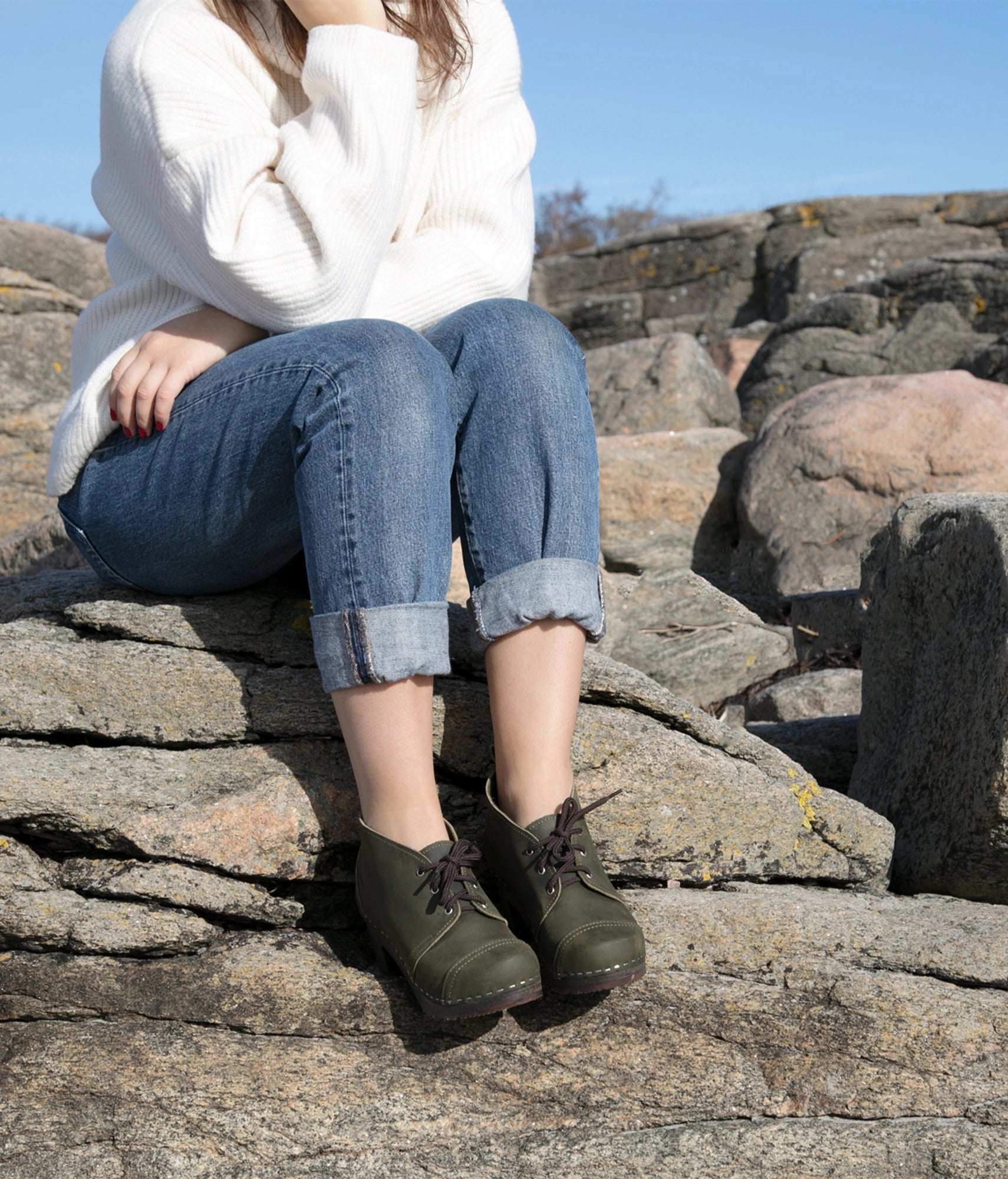 high heeled chukka clog boots in olive green nubuck leather stapled on a dark wooden base with brown laces