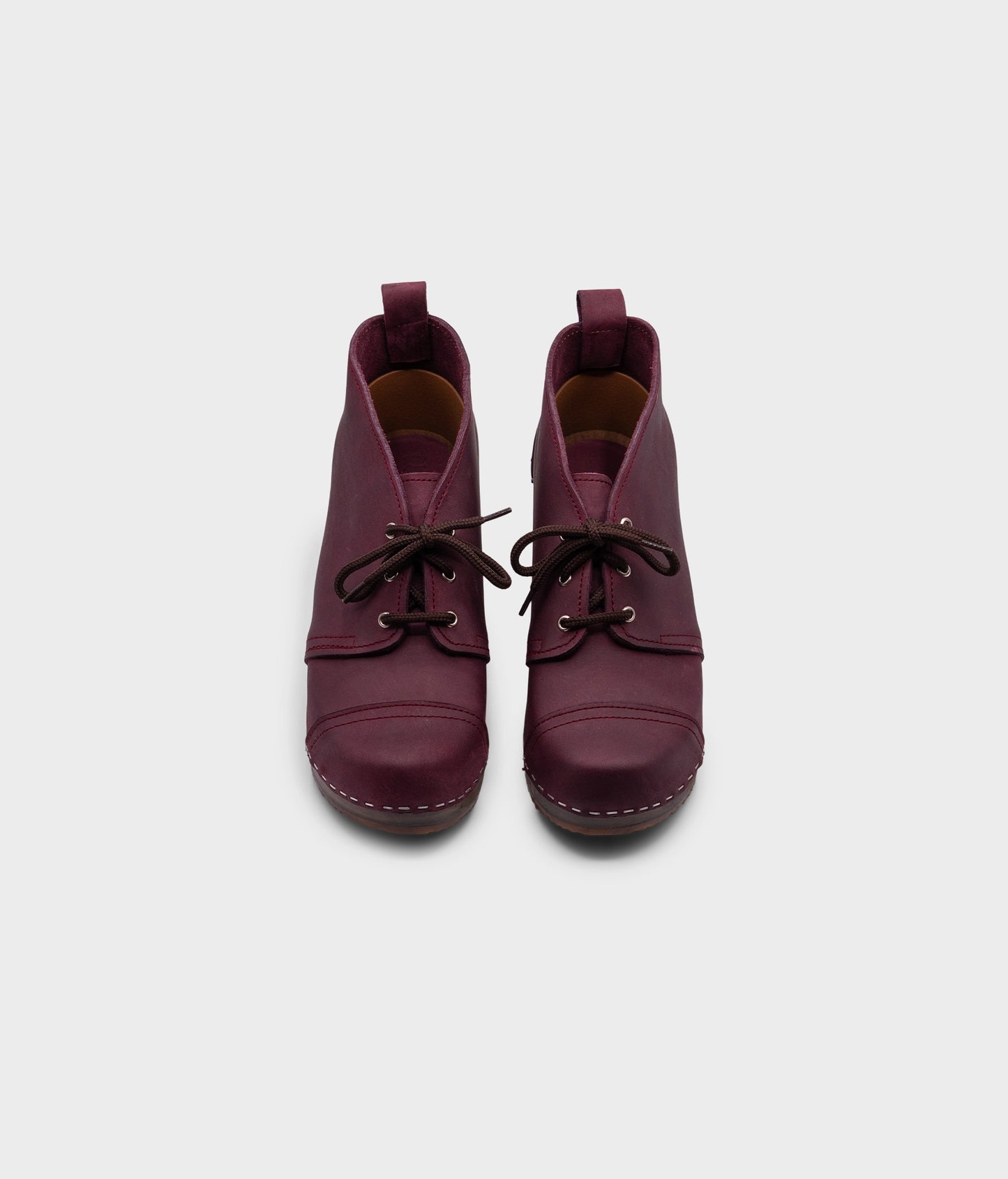 high heeled chukka clog boots in purple plum nubuck leather stapled on a dark wooden base with brown laces