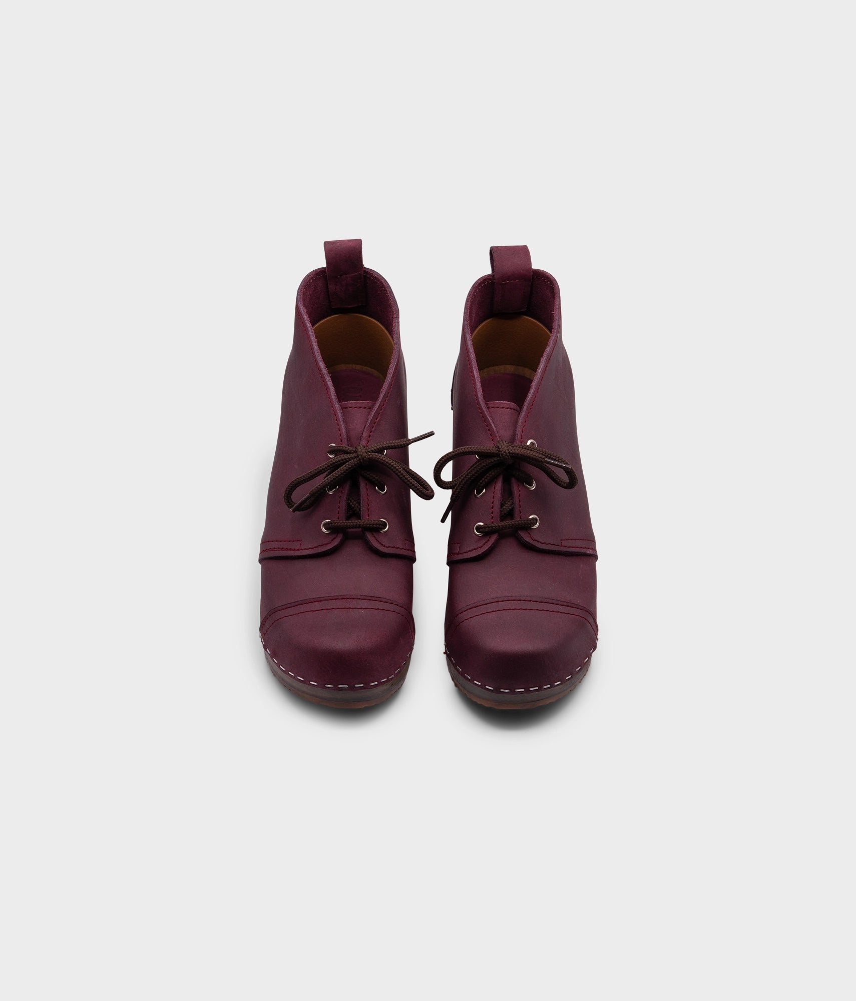 high heeled chukka clog boots in purple plum nubuck leather stapled on a dark wooden base with brown laces