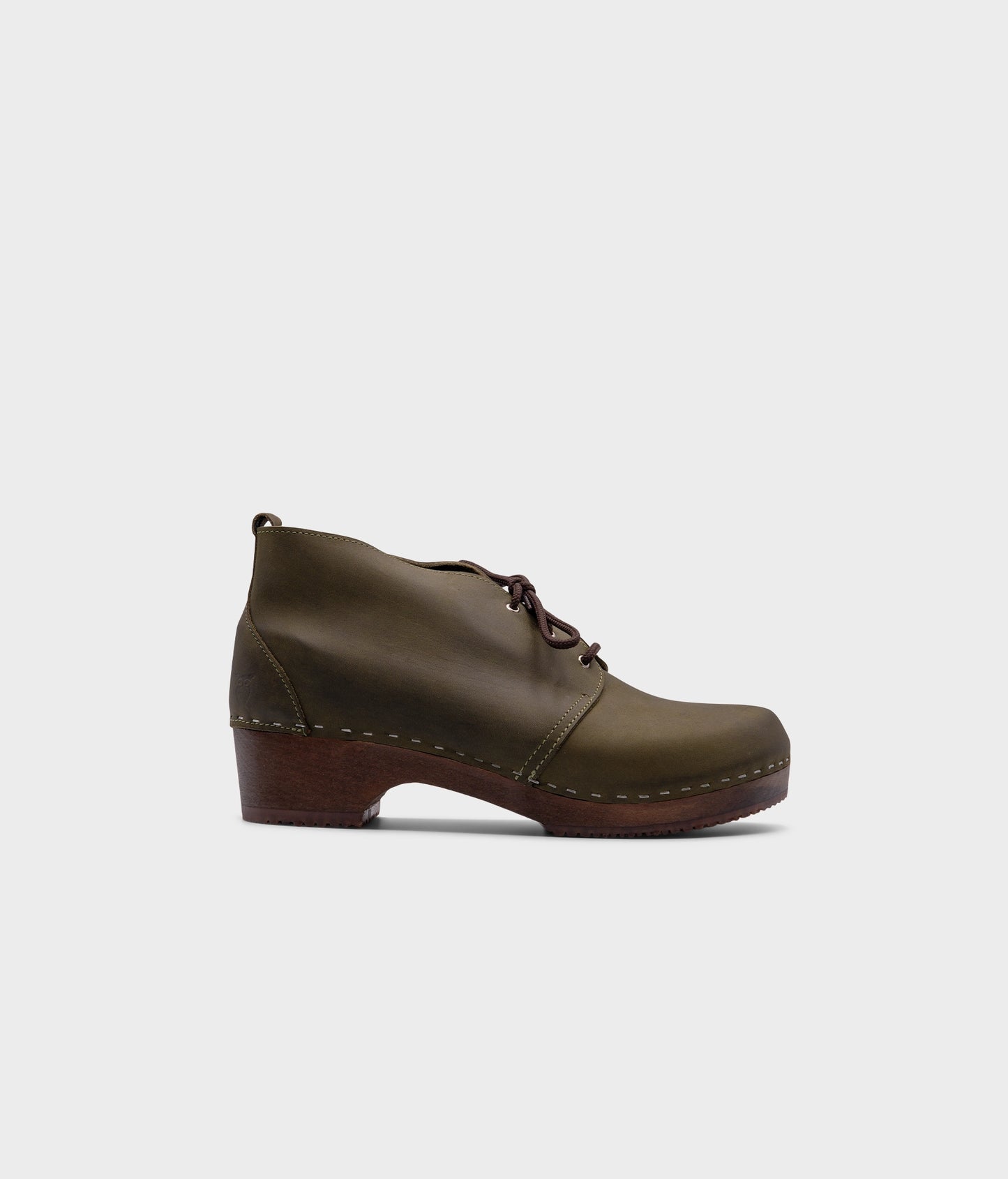 low heeled mens chukka clog boots in olive green nubuck leather stapled on a dark wooden base with brown laces