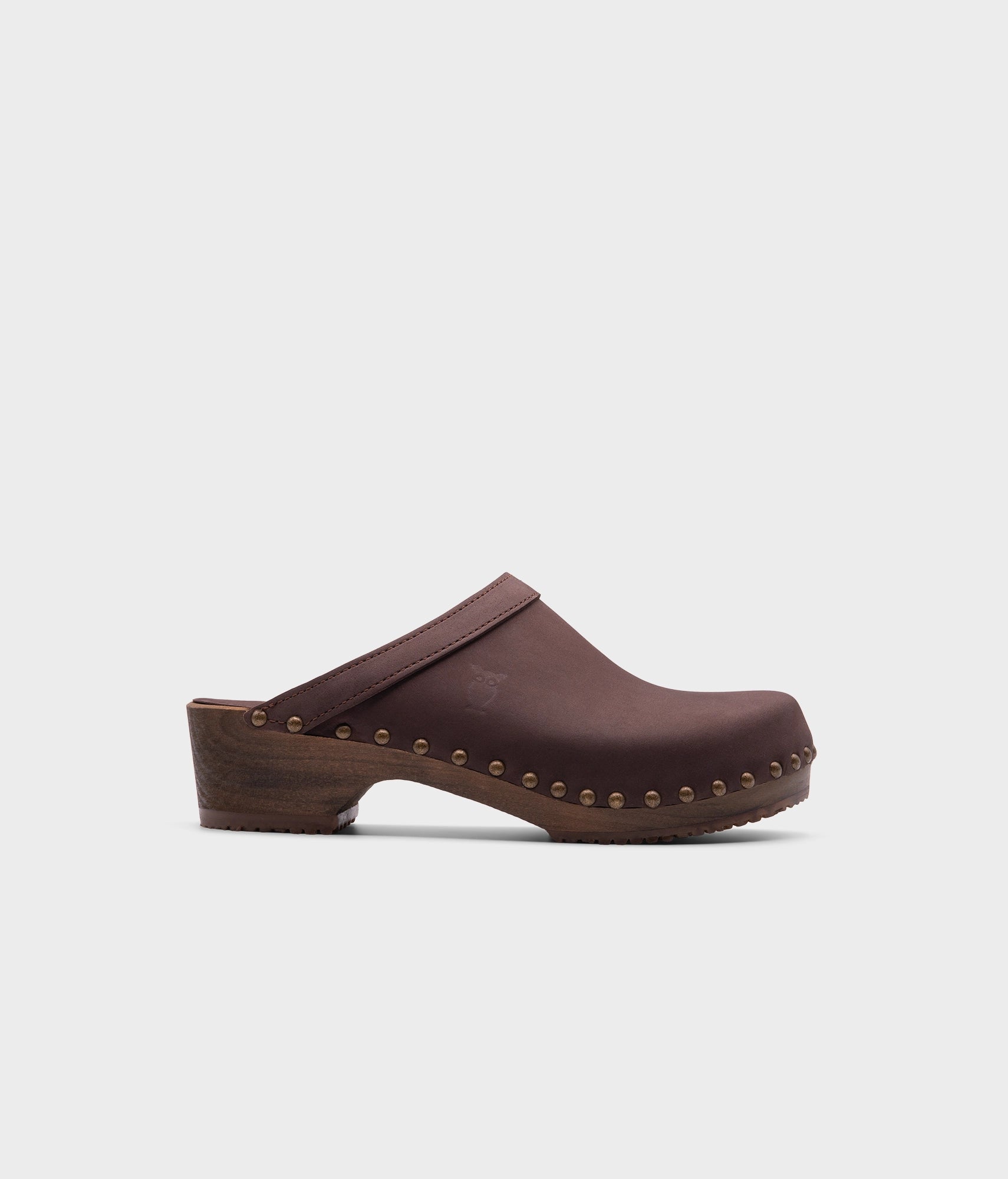 low heeled clog mules in fudge nubuck leather stapled on a dark wooden base with brass gold studs