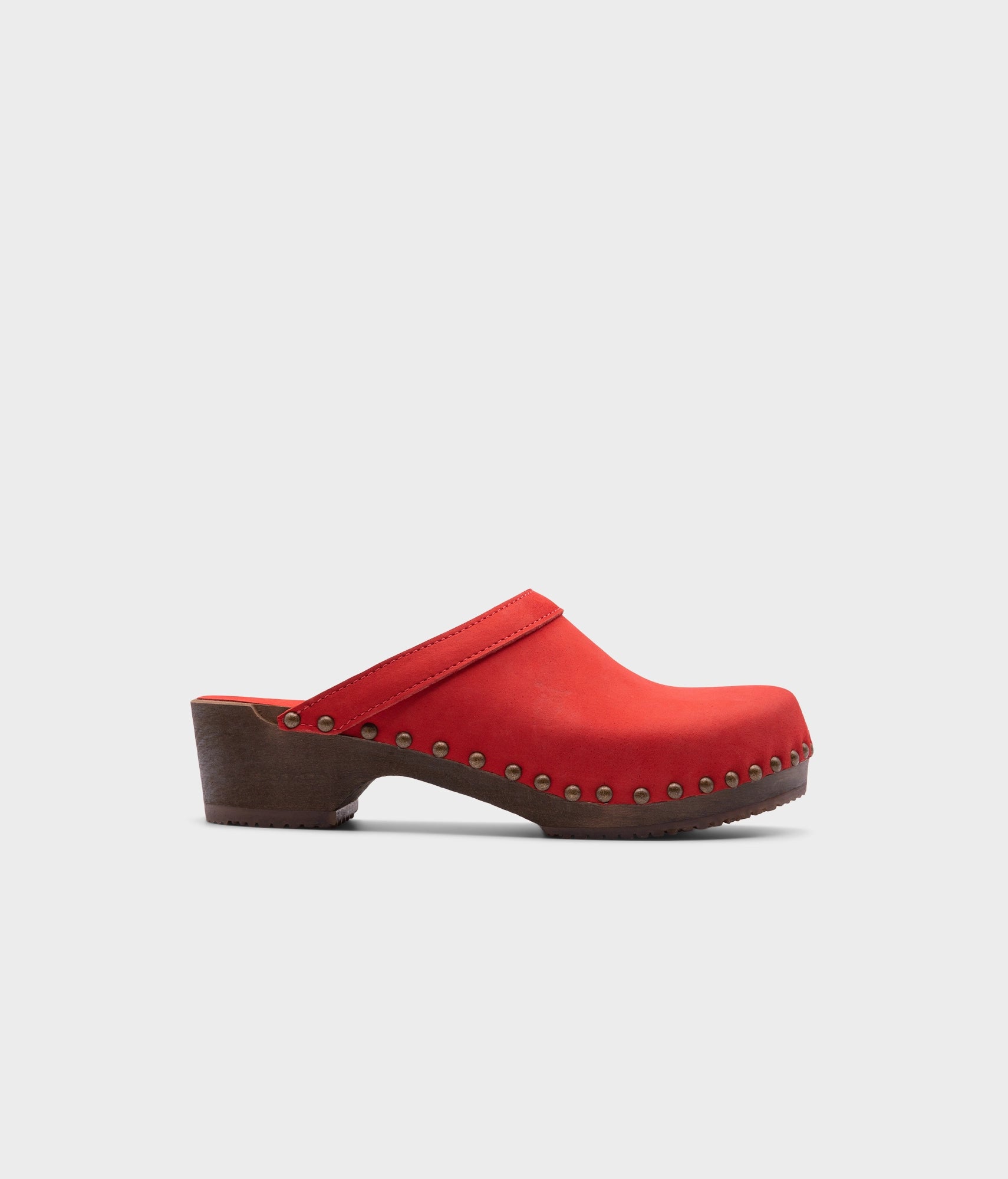 low heeled clog mules in red nubuck leather stapled on a dark wooden base with brass gold studs