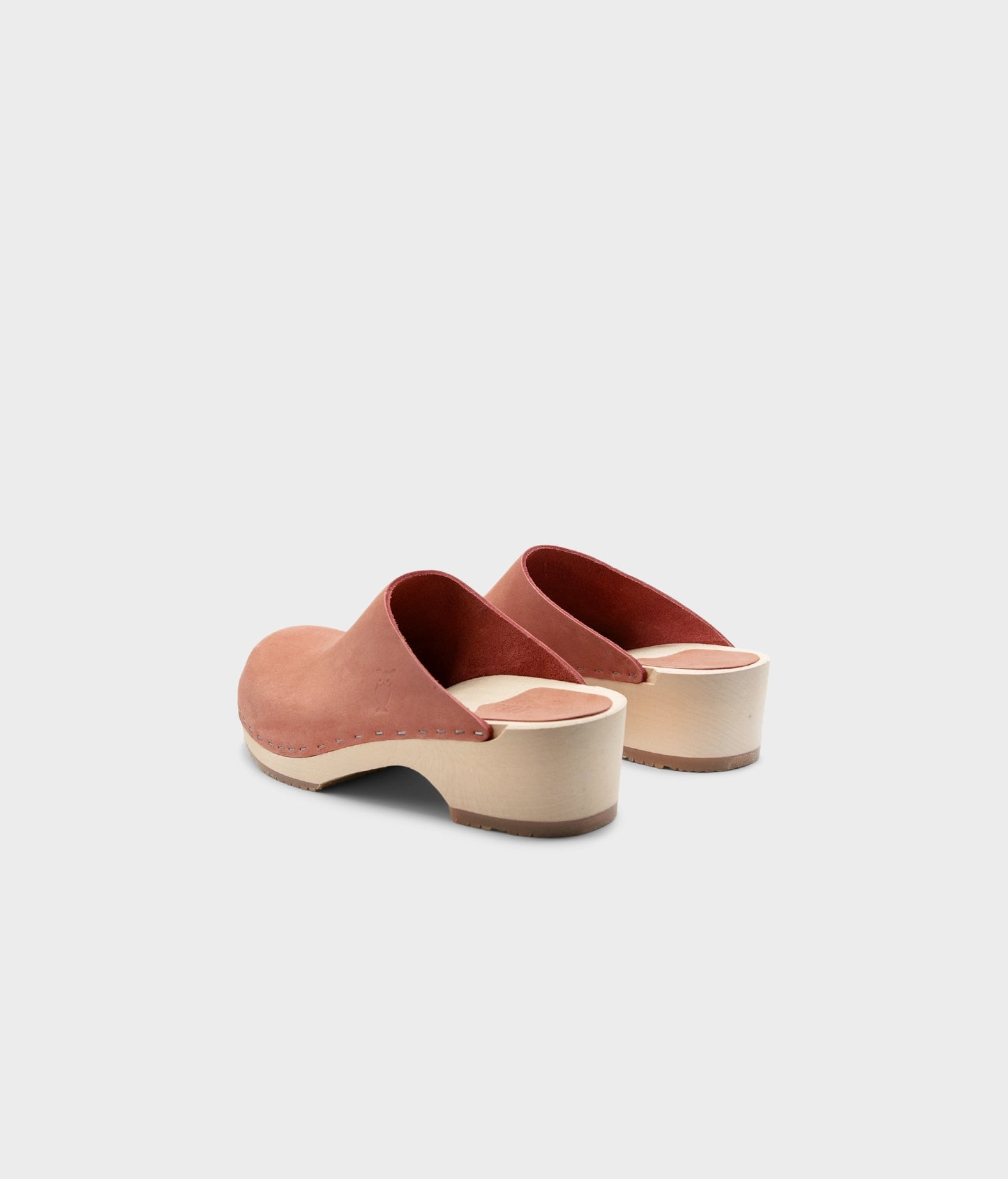 low heeled minimalistic clog mules in blush pink nubuck leather stapled on a light wooden base