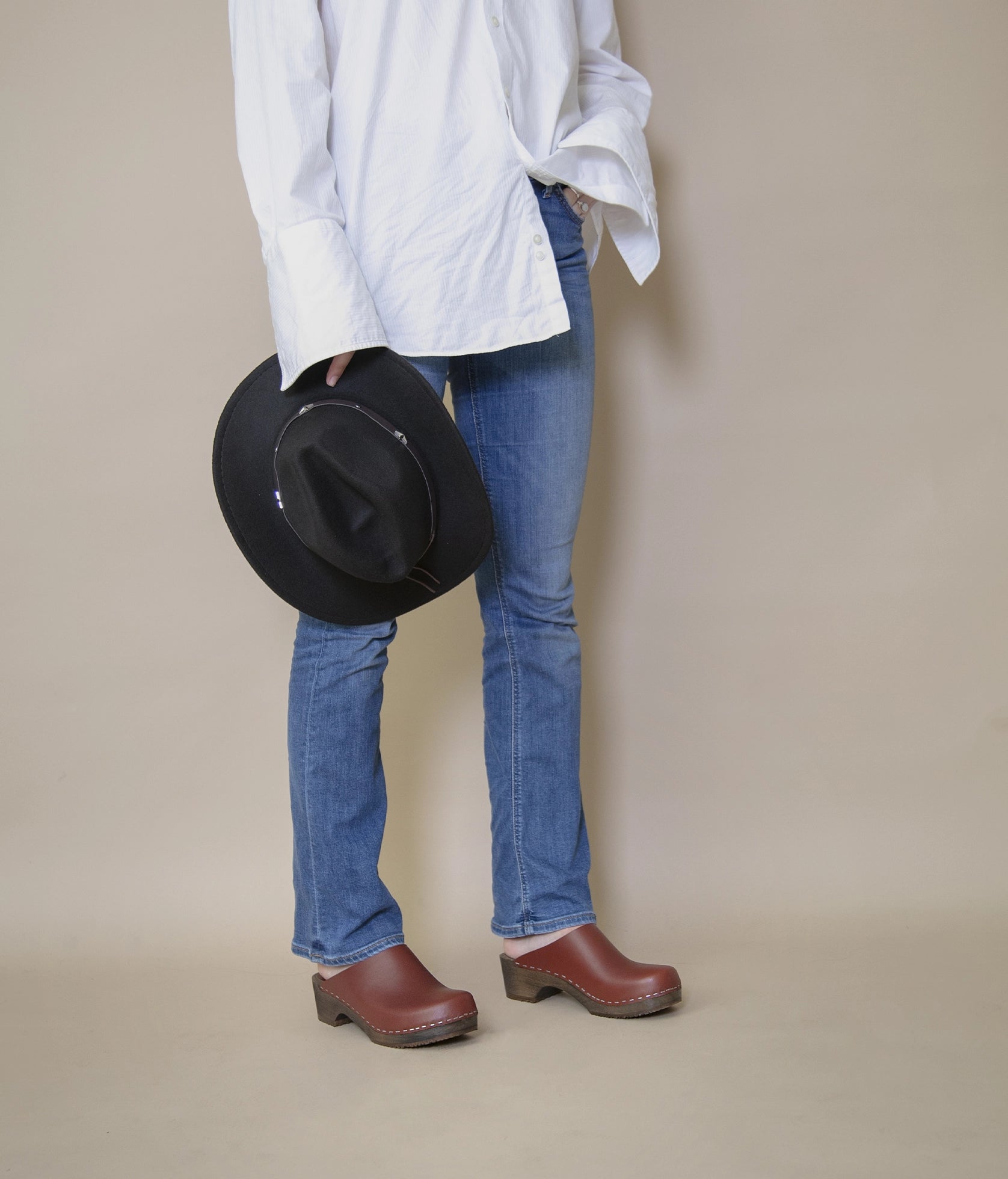 low heeled minimalistic clog mules in cognac vegetable tanned leather stapled on a dark wooden base