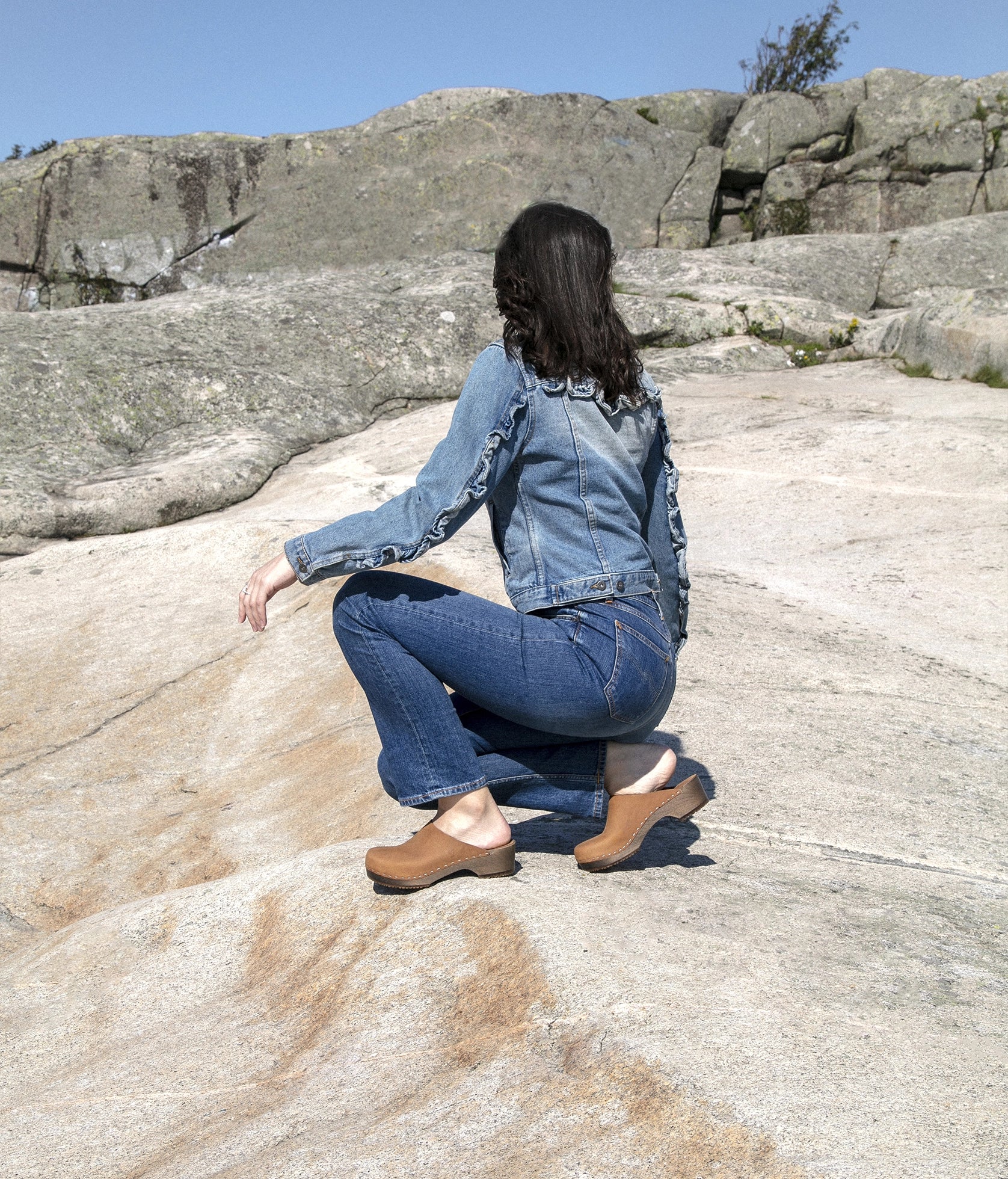 low heeled minimalistic clog mules in dexter tan nubuck leather stapled on a dark wooden base