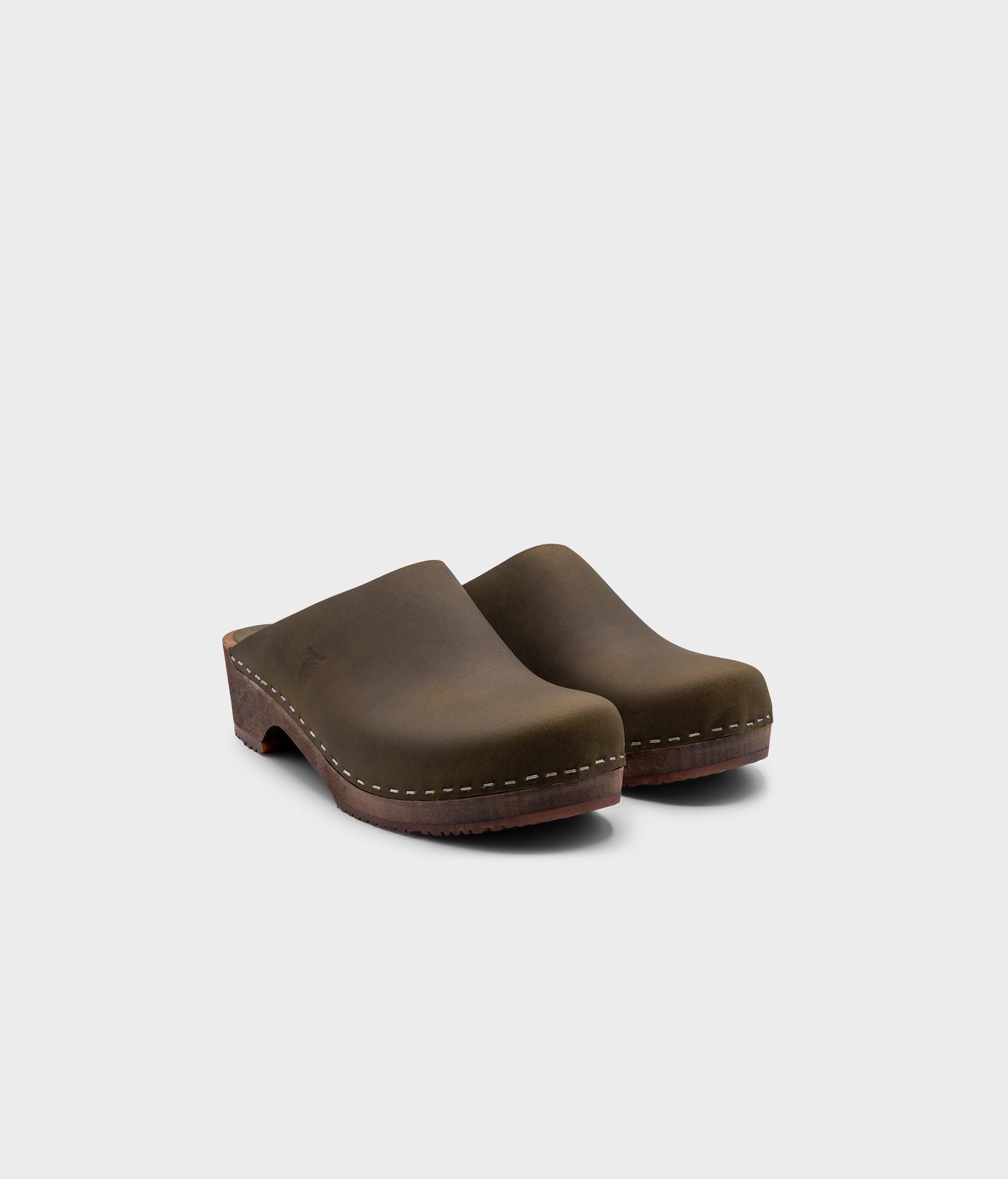 low heeled minimalistic clog mules in olive nubuck leather stapled on a dark wooden base