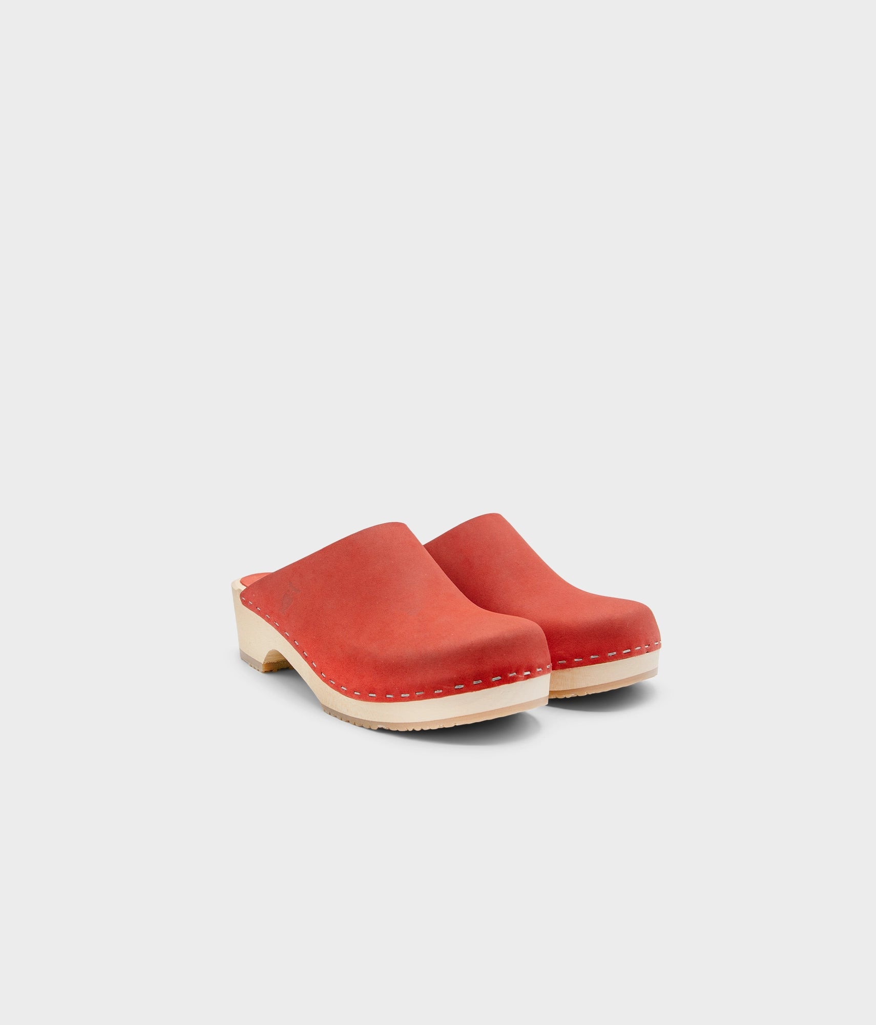 low heeled minimalistic clog mules in red nubuck leather stapled on a light wooden base