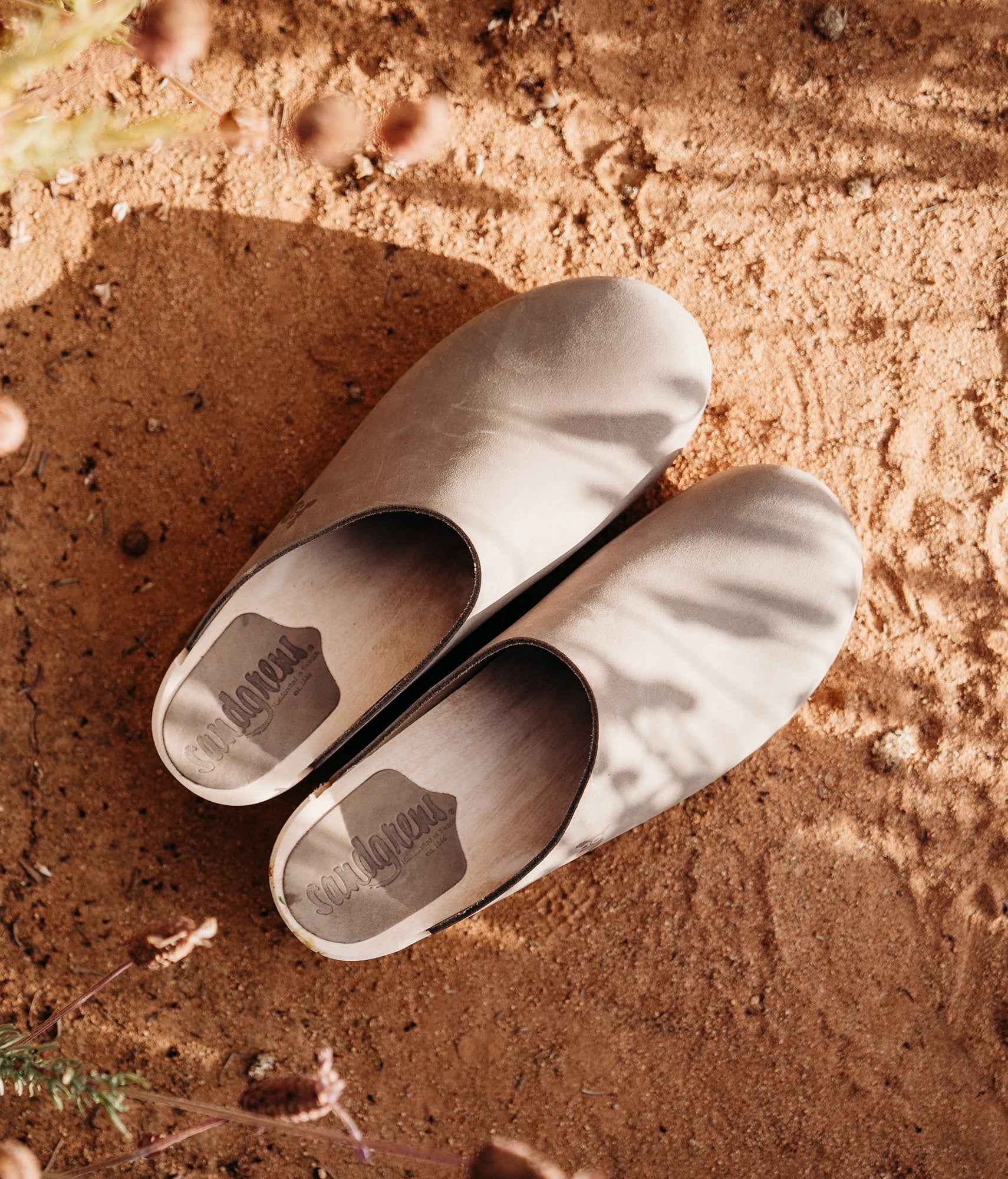 low heeled minimalistic clog mules in stone grey nubuck leather stapled on a light wooden base