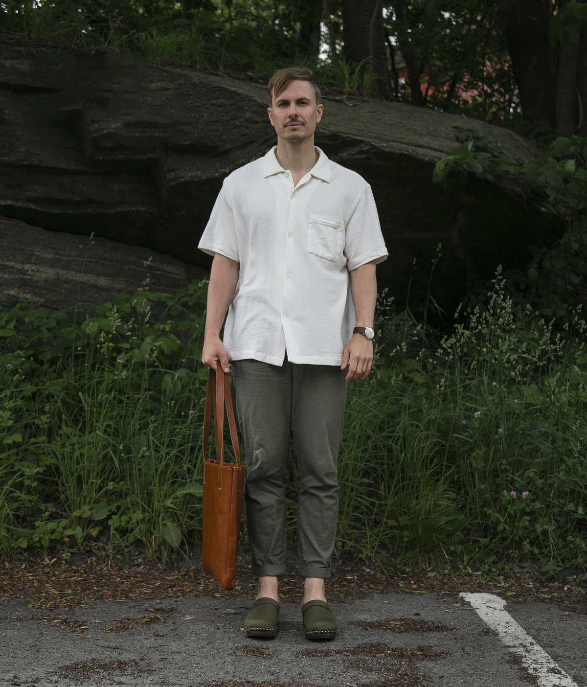 Man standing in front of  greenery in Olive clogs