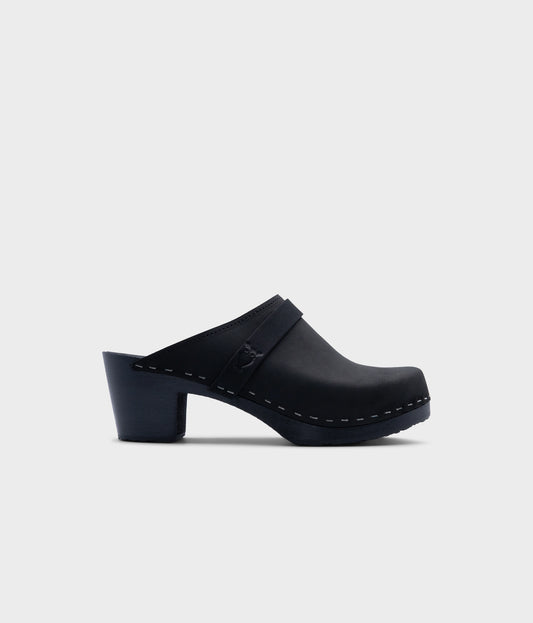 classic high heeled clog mule in black  nubuck leather stapled on a black wooden base with a leather strap