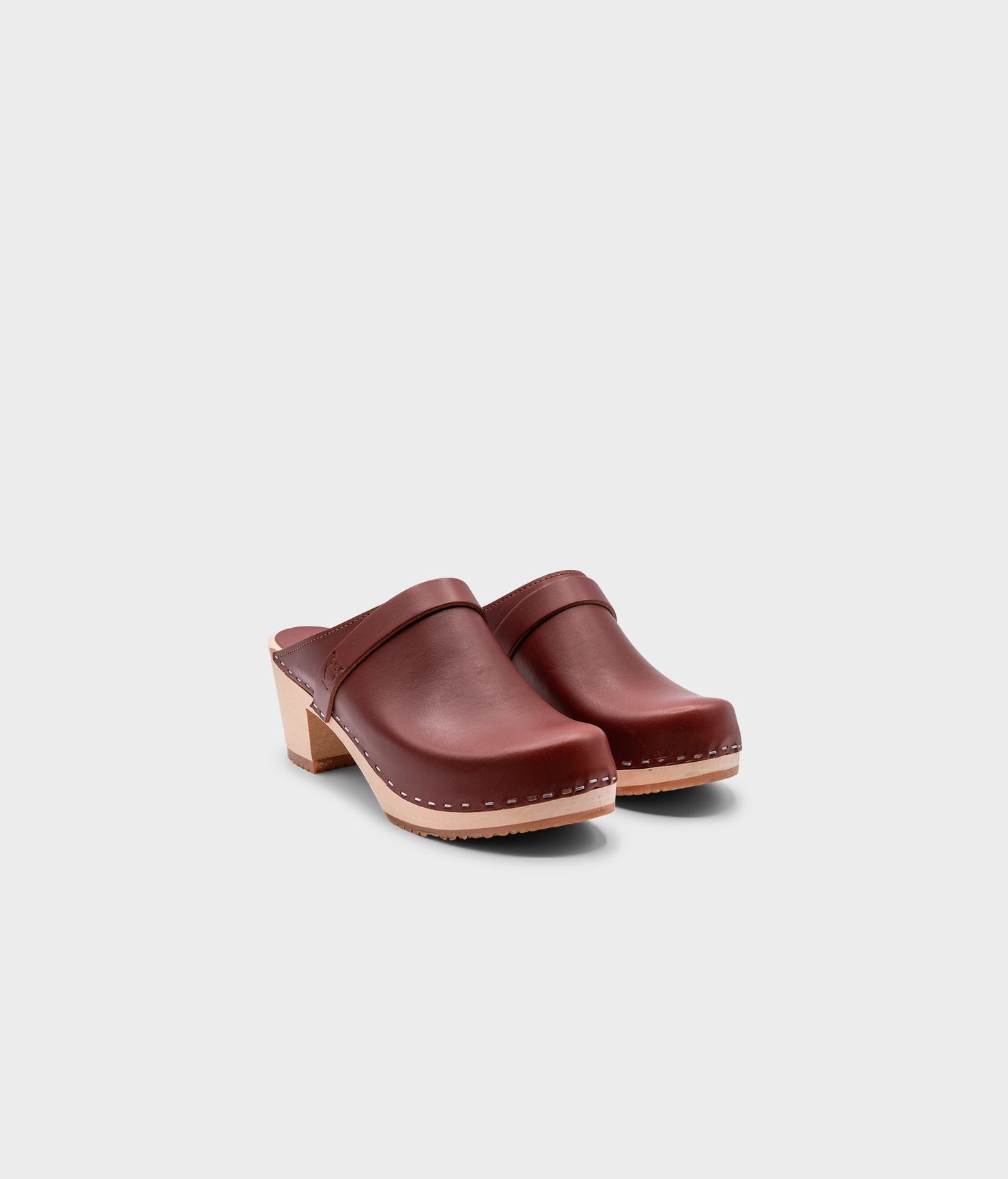 classic high heeled clog mule in cognac red vegetable tanned leather stapled on a light wooden base with a leather strap