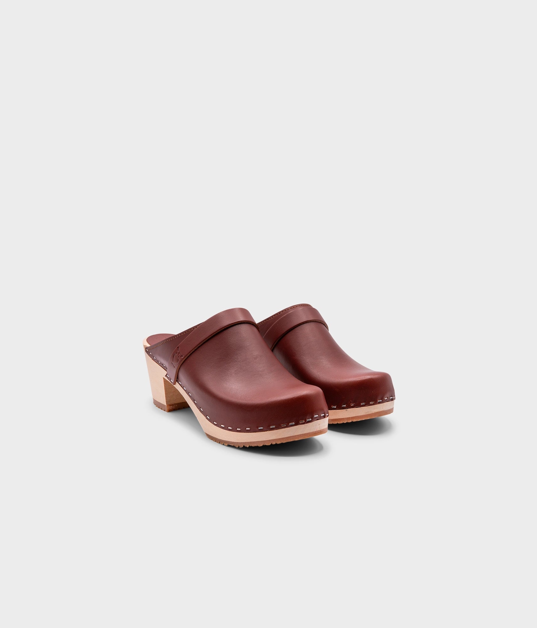 classic high heeled clog mule in cognac red vegetable tanned leather stapled on a light wooden base with a leather strap