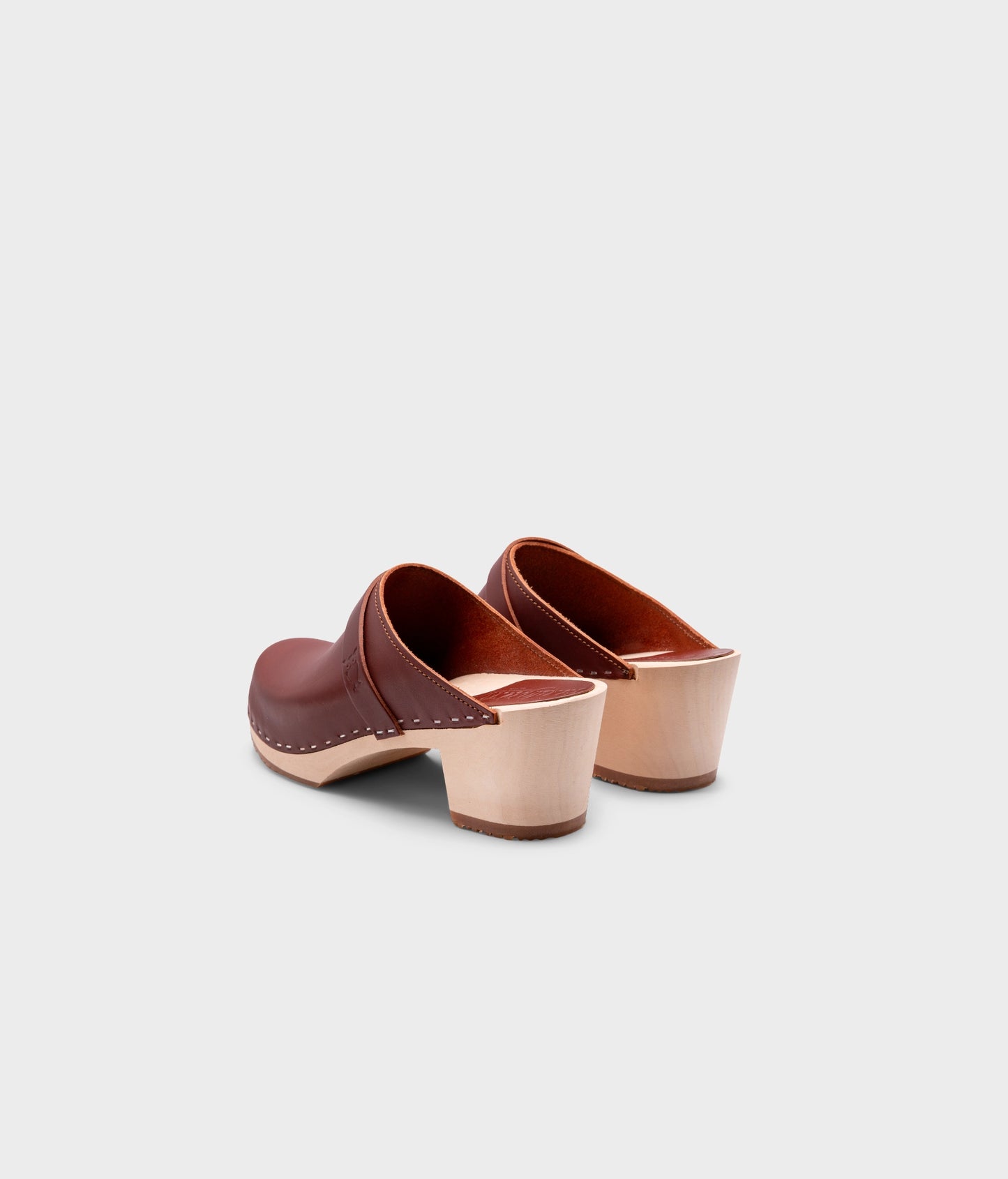 classic high heeled clog mule in cognac red vegetable tanned leather stapled on a light wooden base with a leather strap