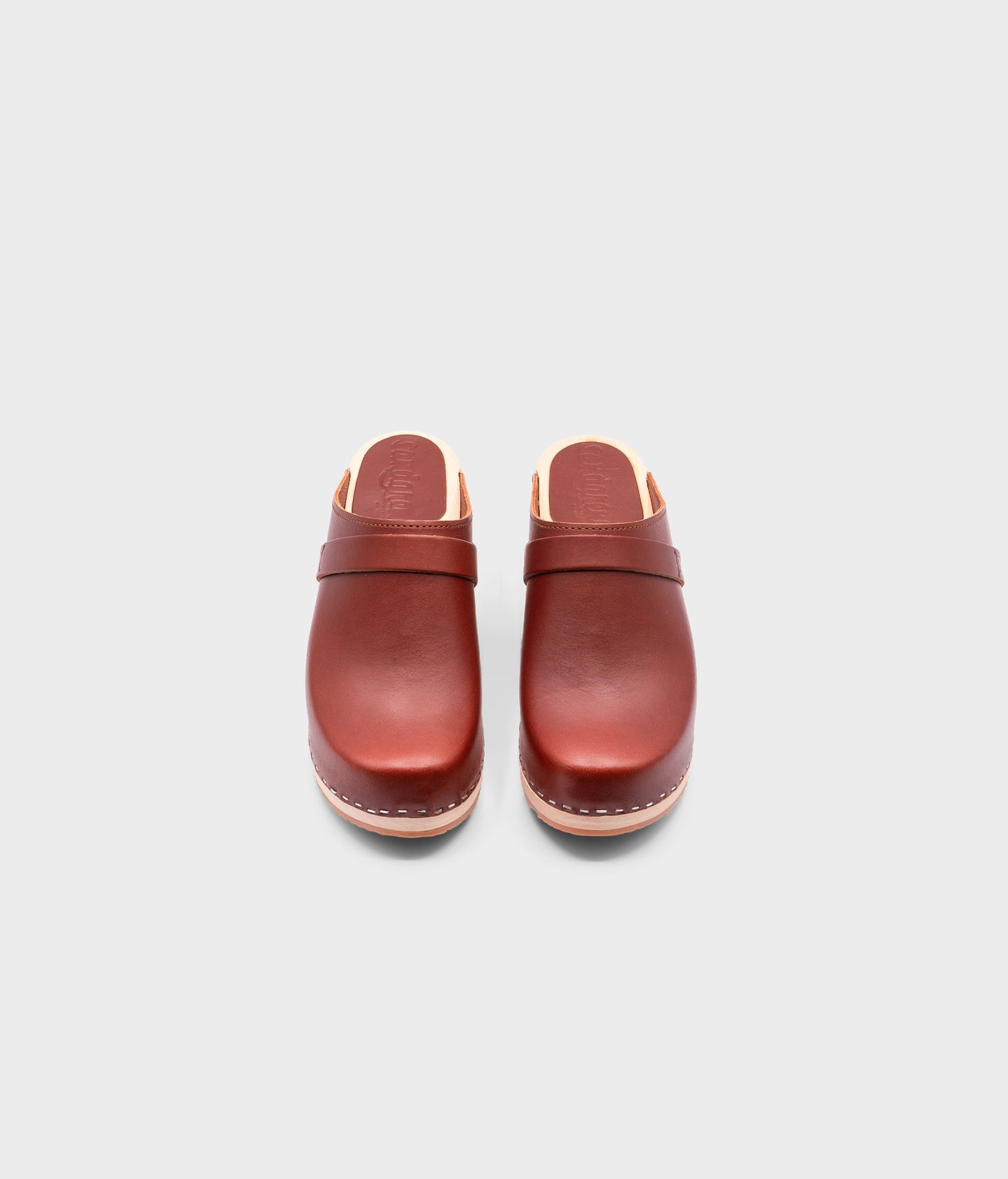 classic high heeled clog mule in cognac red vegetable tanned leather stapled on a light wooden base with a leather strap