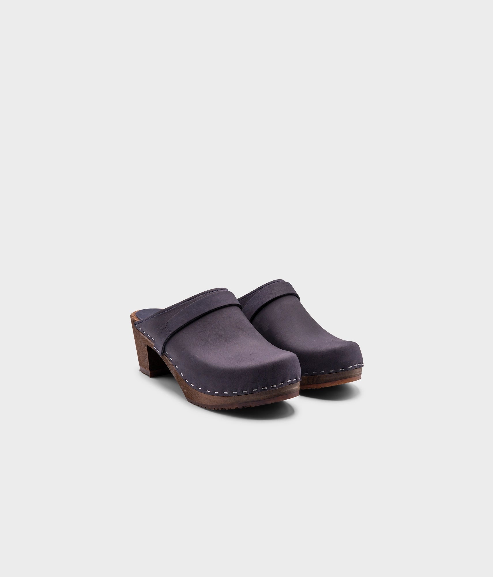 classic high heeled clog mule in navy blue nubuck leather stapled on a dark wooden base with a leather strap