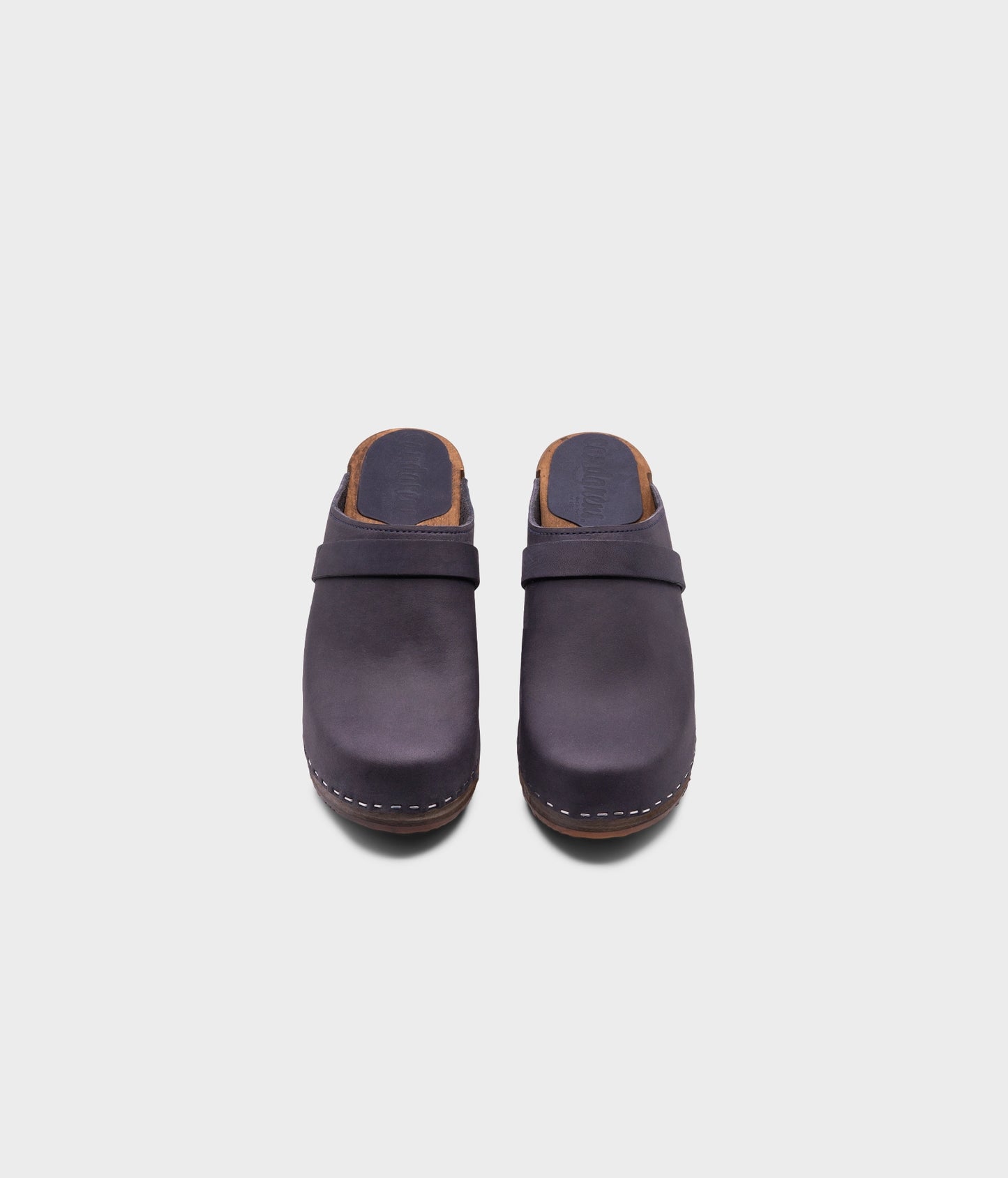 classic high heeled clog mule in navy blue nubuck leather stapled on a dark wooden base with a leather strap