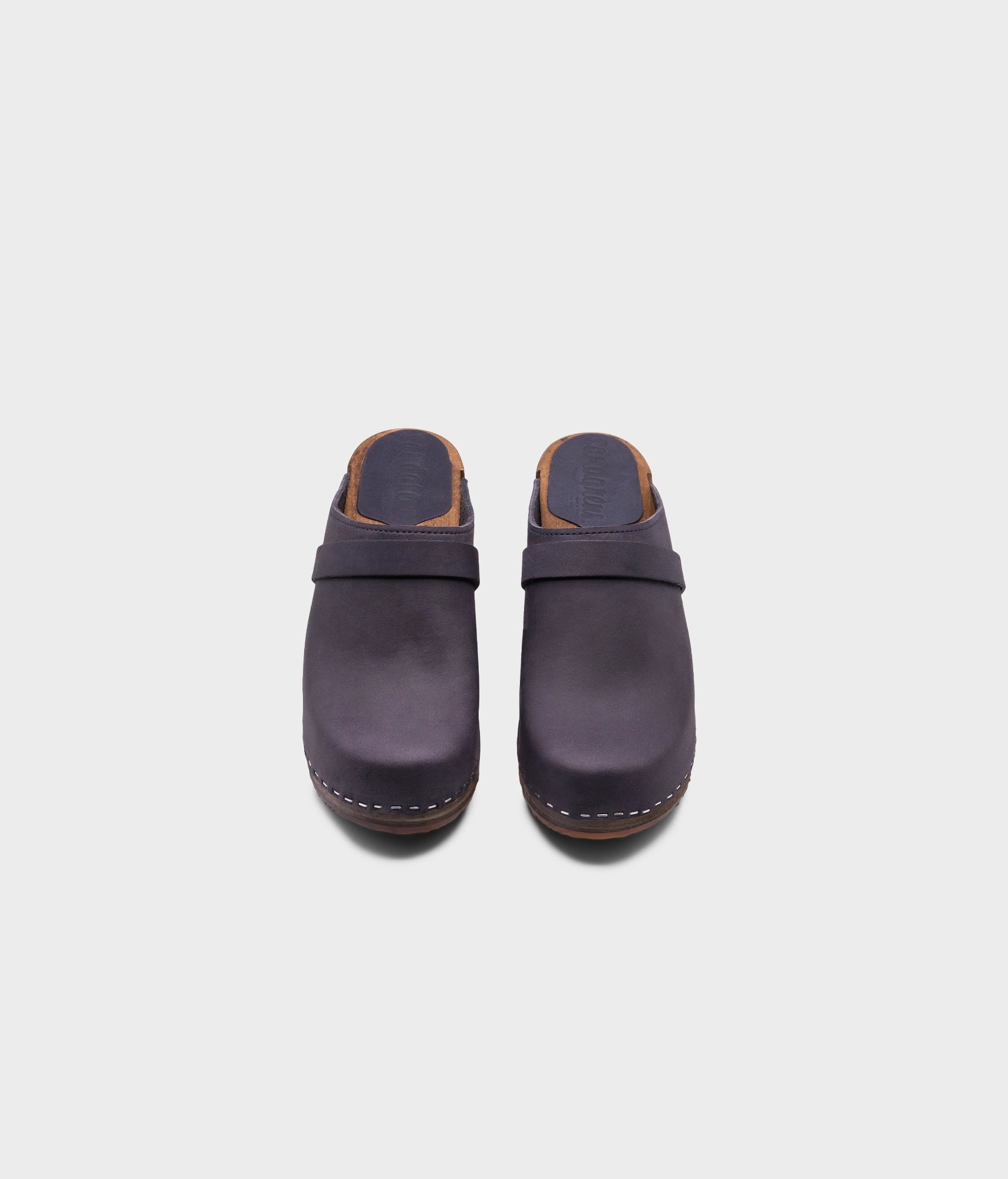 classic high heeled clog mule in navy blue nubuck leather stapled on a dark wooden base with a leather strap