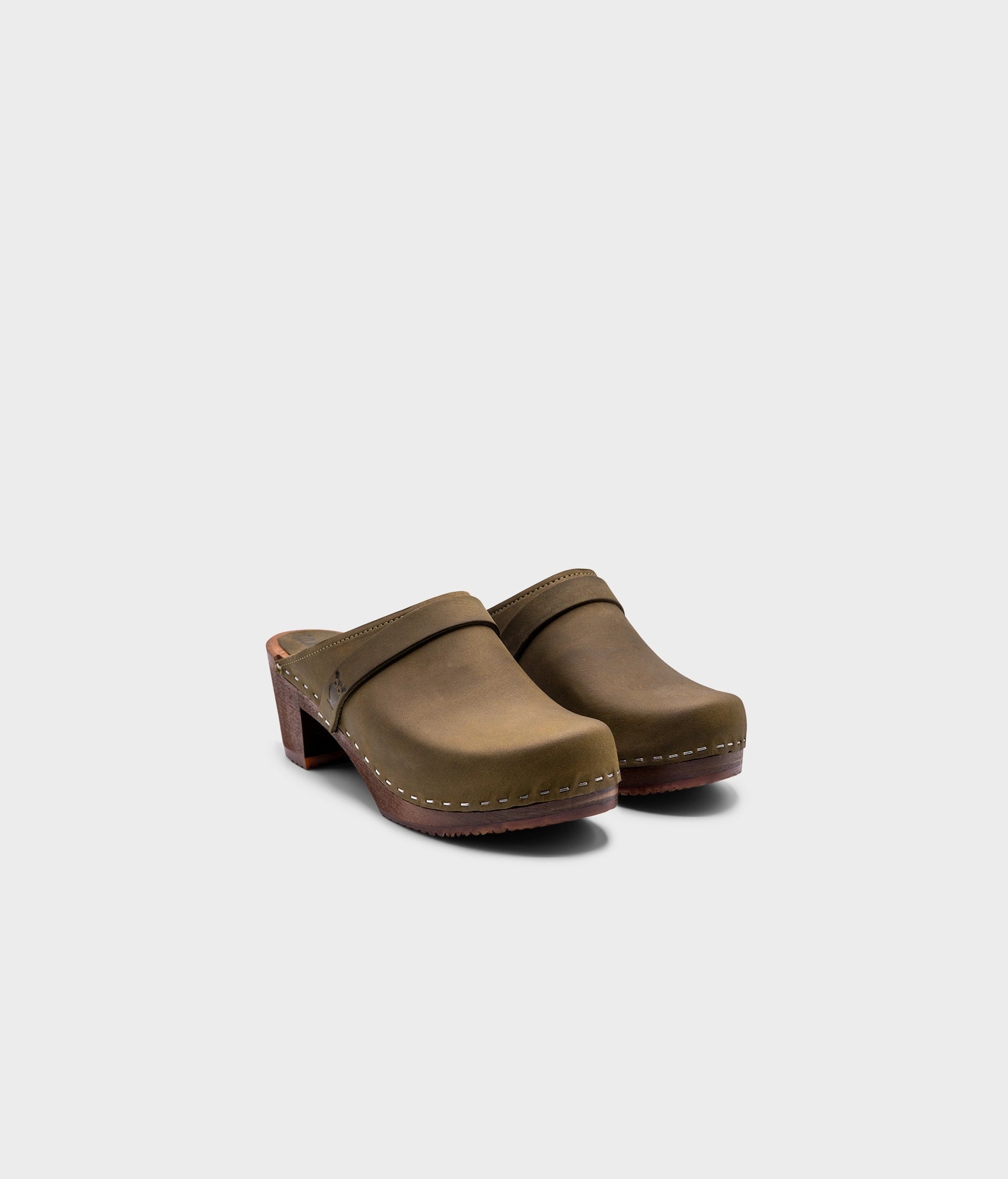classic high heeled clog mule in olive green nubuck leather stapled on a dark wooden base with a leather strap