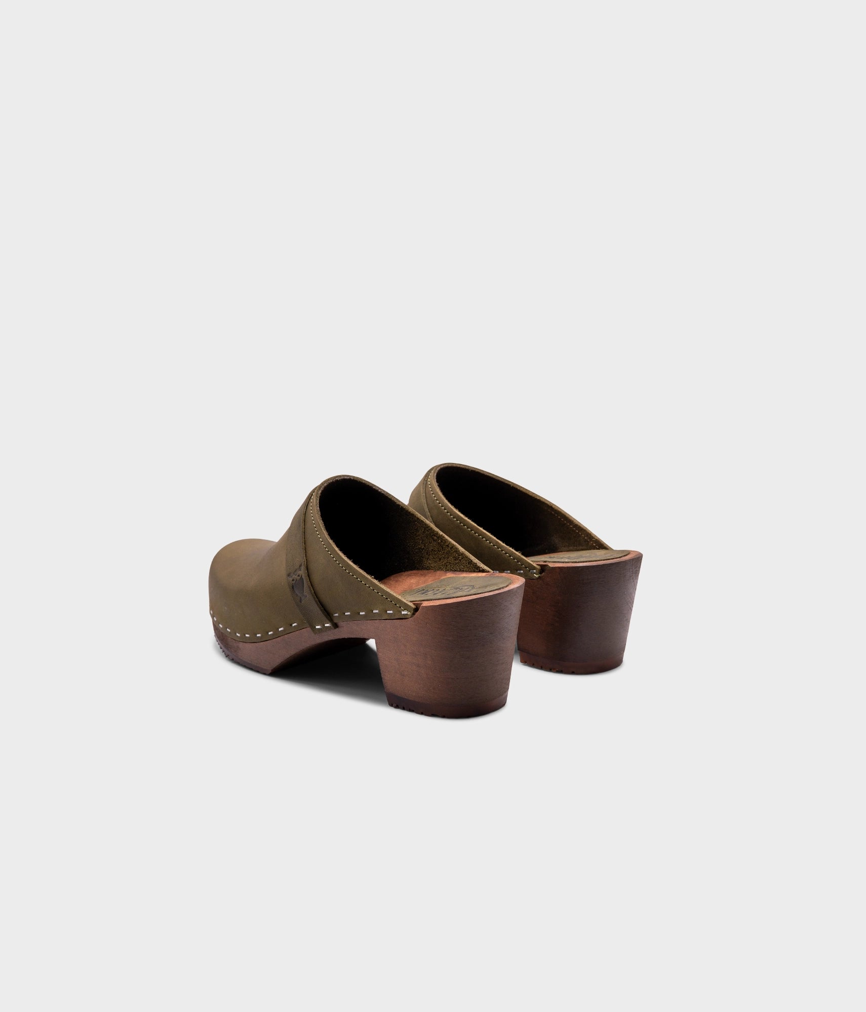 classic high heeled clog mule in olive green nubuck leather stapled on a dark wooden base with a leather strap