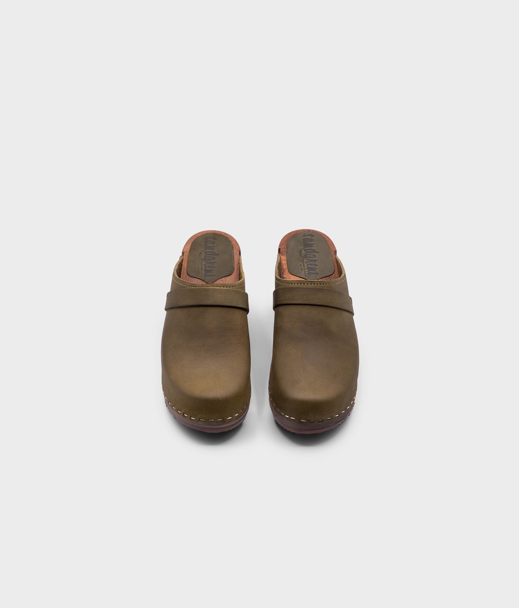 classic high heeled clog mule in olive green nubuck leather stapled on a dark wooden base with a leather strap