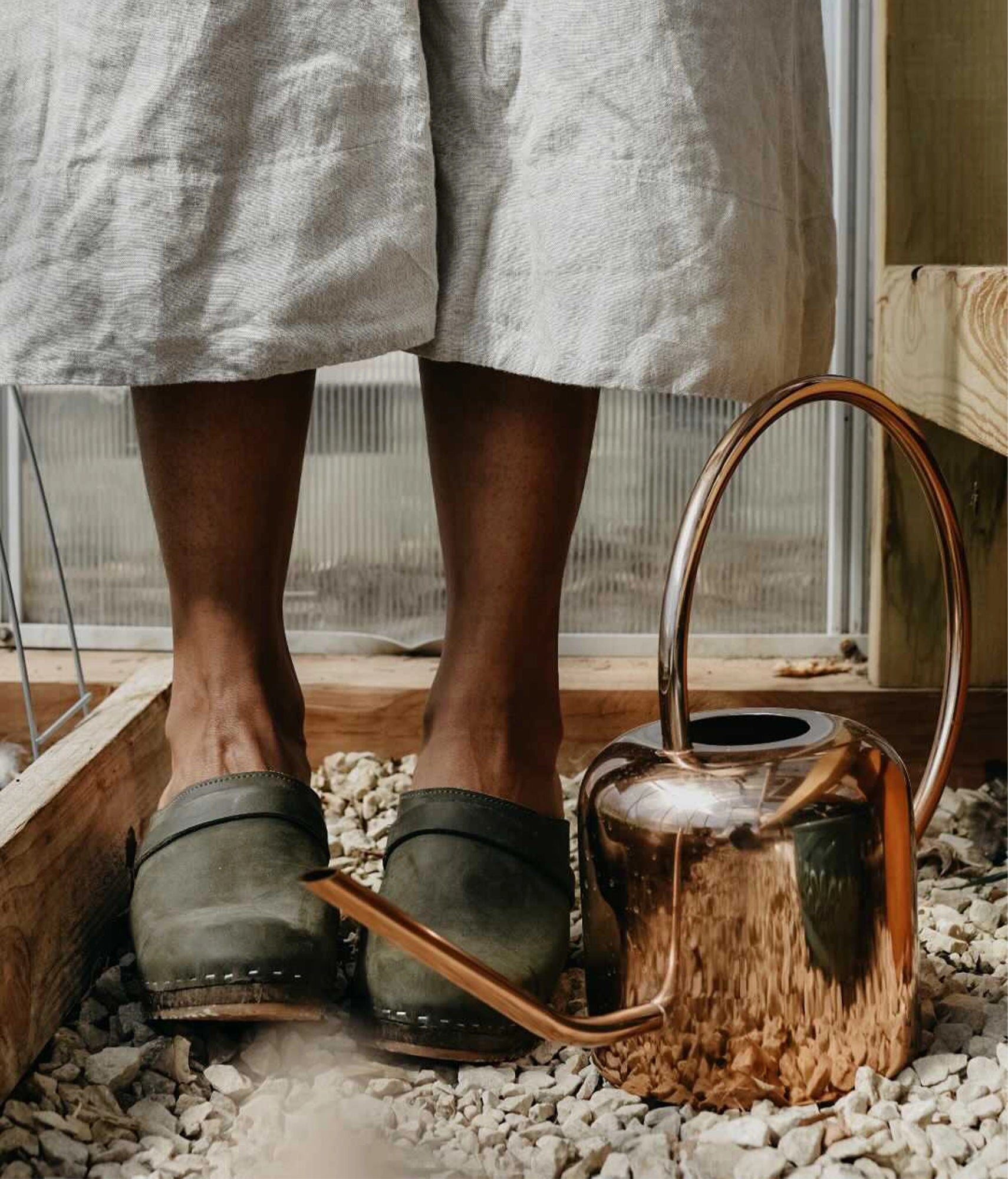 classic high heeled clog mule in olive green nubuck leather stapled on a dark wooden base with a leather strap