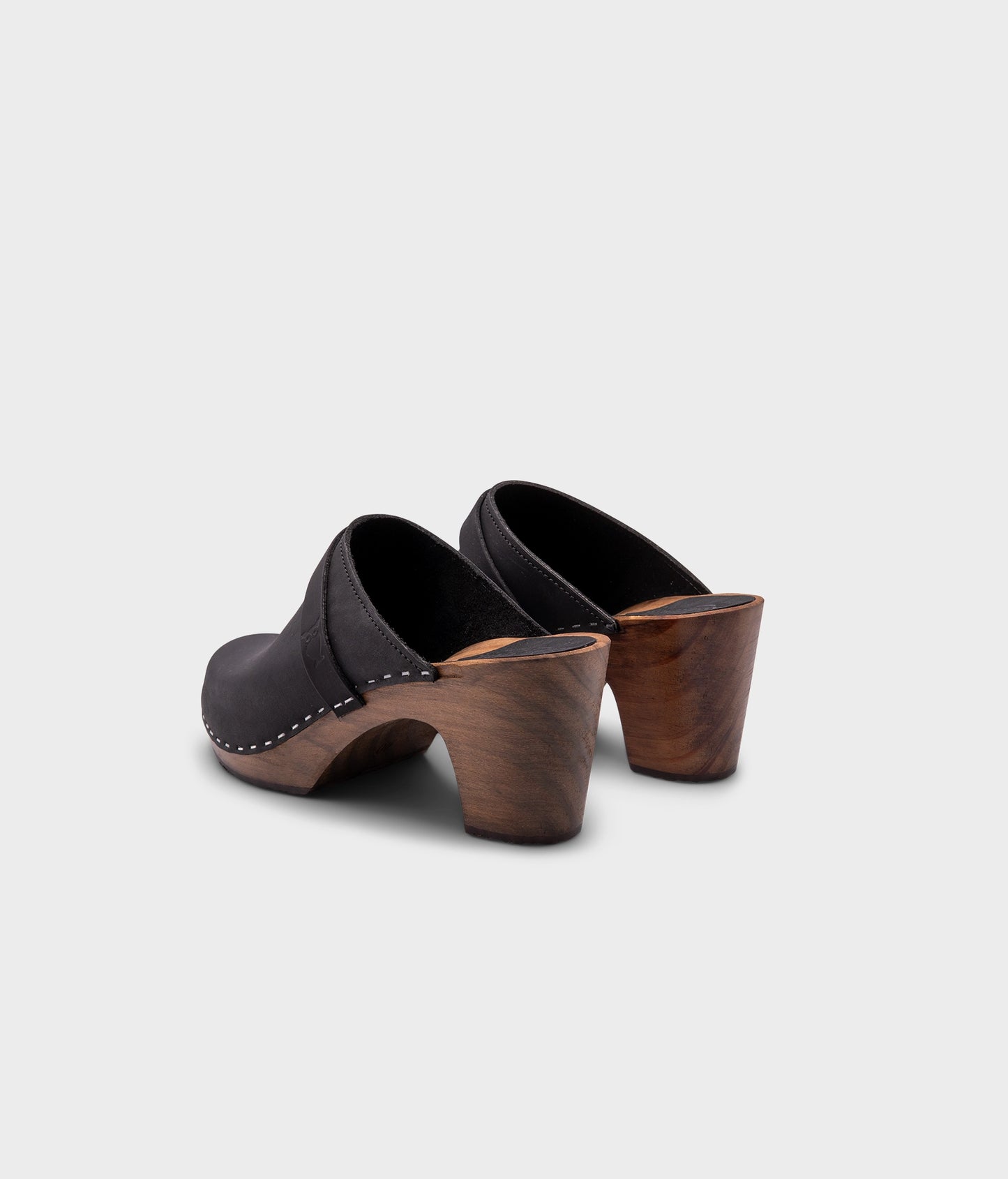 classic high rise heel clog mule in black nubuck leather stapled on a dark wooden base