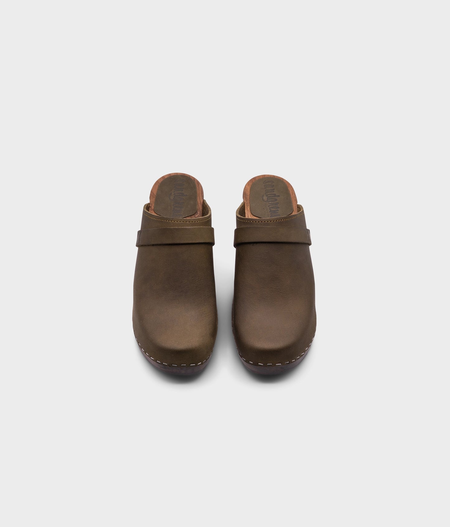 classic high rise heel clog mule in olive green nubuck leather stapled on a dark wooden base