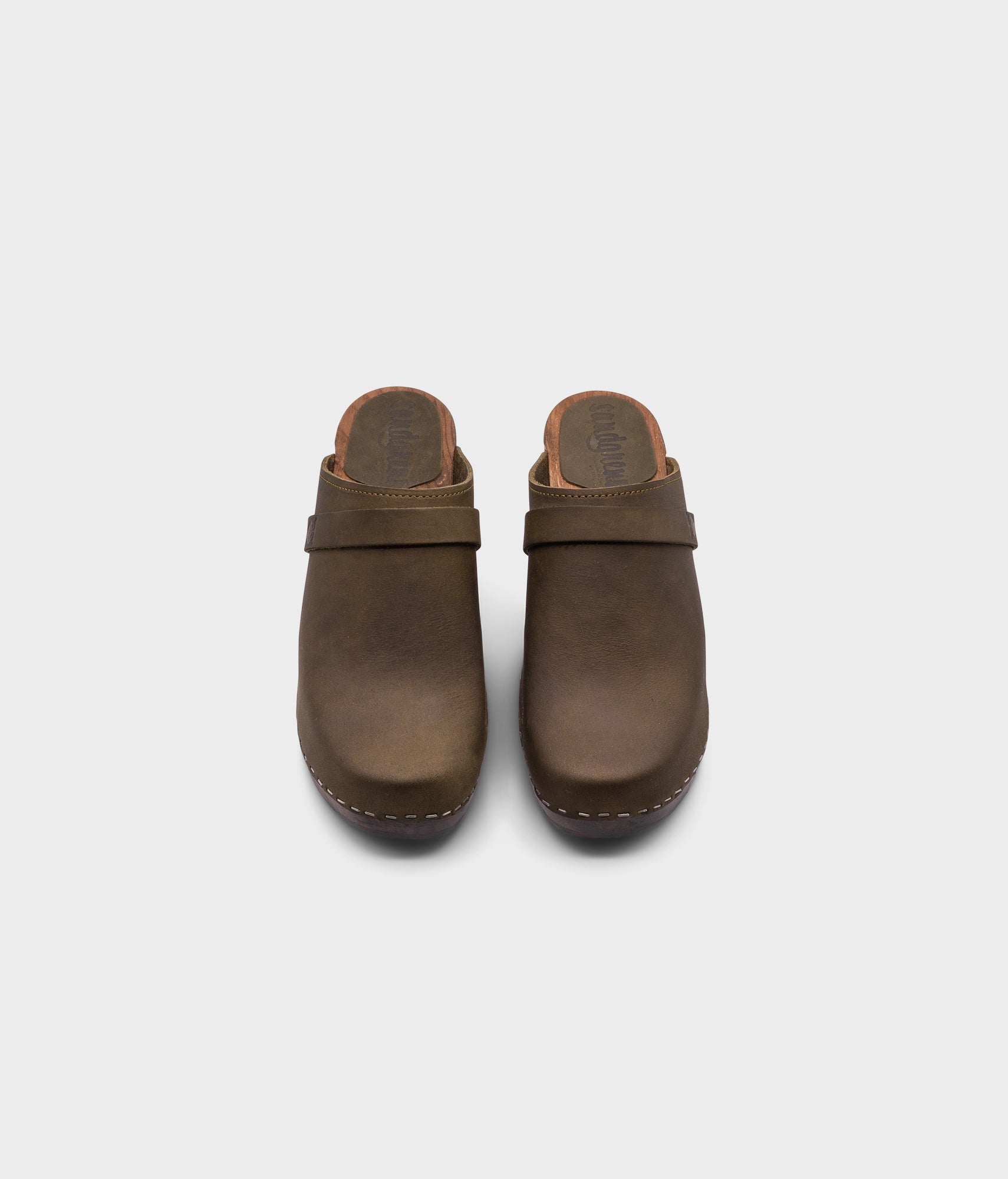 classic high rise heel clog mule in olive green nubuck leather stapled on a dark wooden base