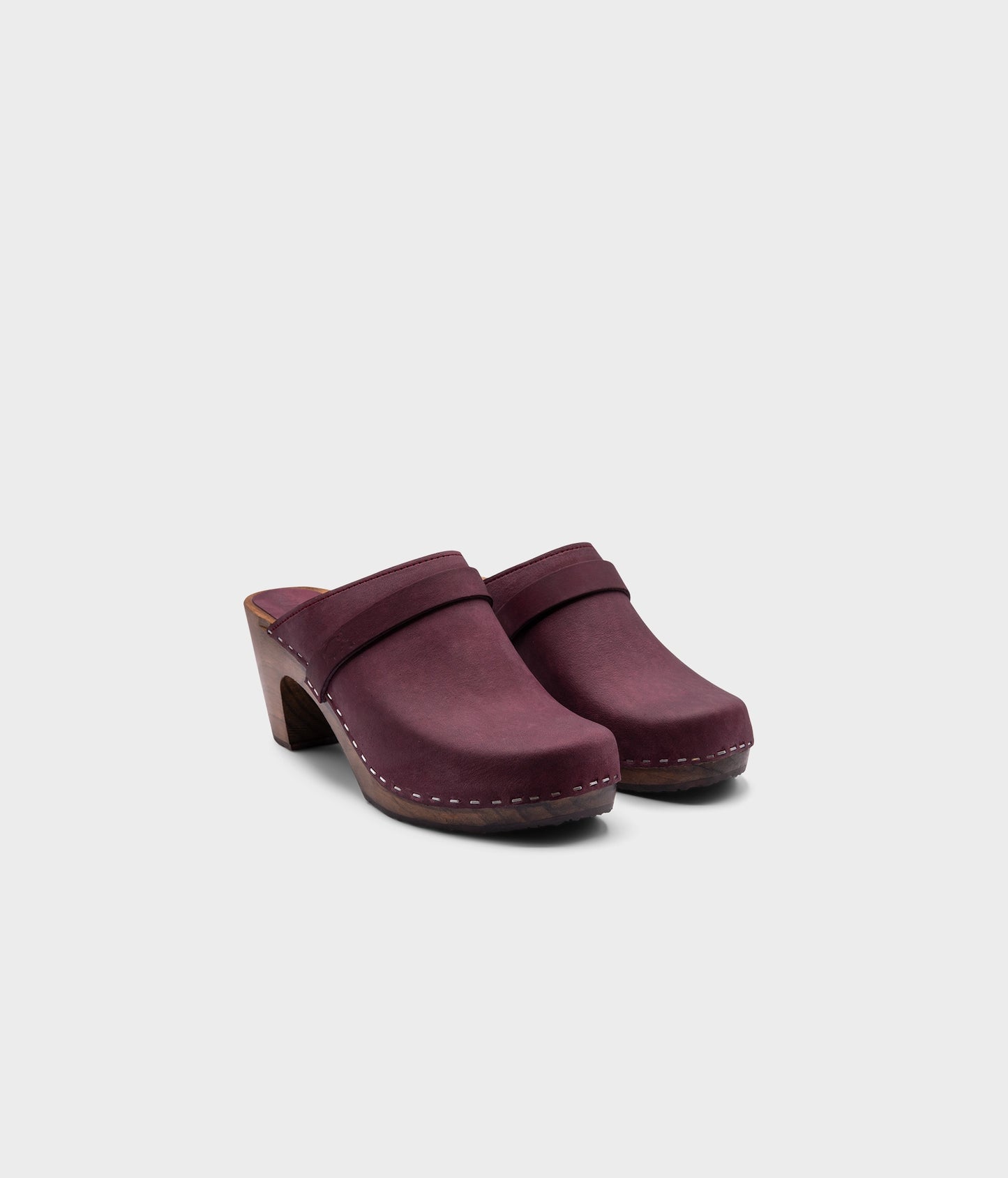 classic high rise heel clog mule in dark purple nubuck leather stapled on a dark wooden base