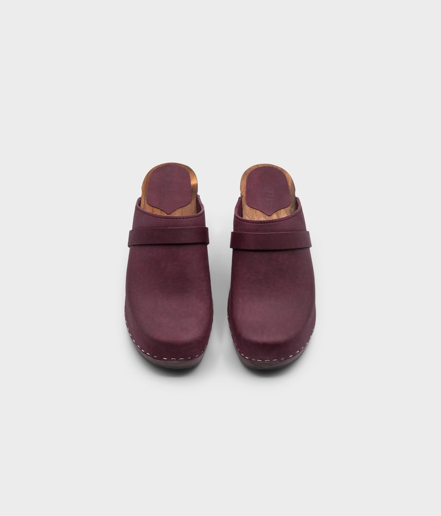 classic high rise heel clog mule in dark purple nubuck leather stapled on a dark wooden base