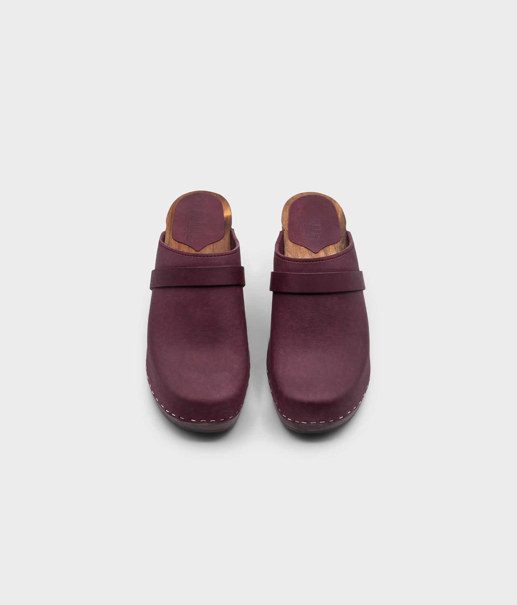 classic high rise heel clog mule in dark purple nubuck leather stapled on a dark wooden base