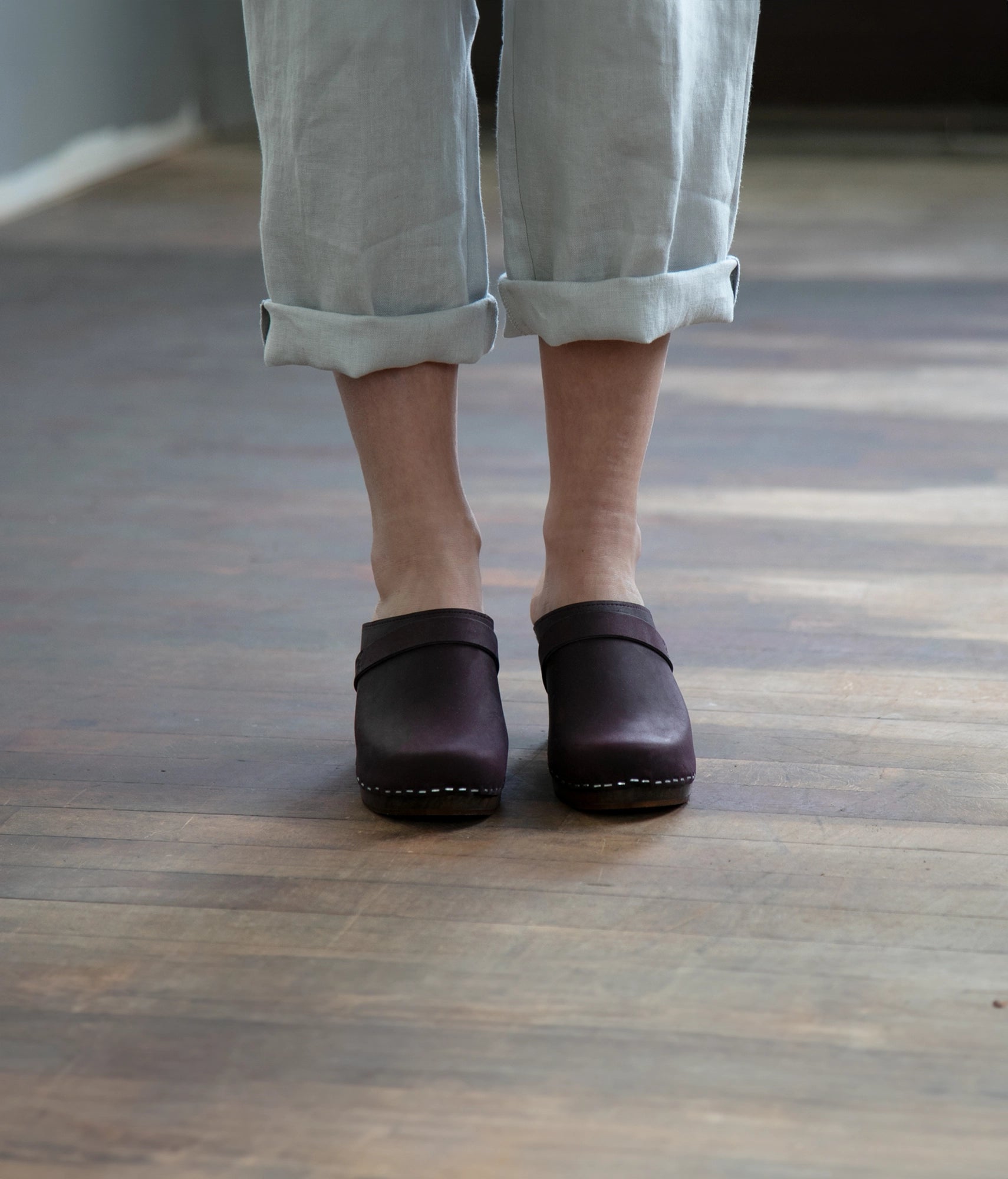 classic high rise heel clog mule in dark purple nubuck leather stapled on a dark wooden base