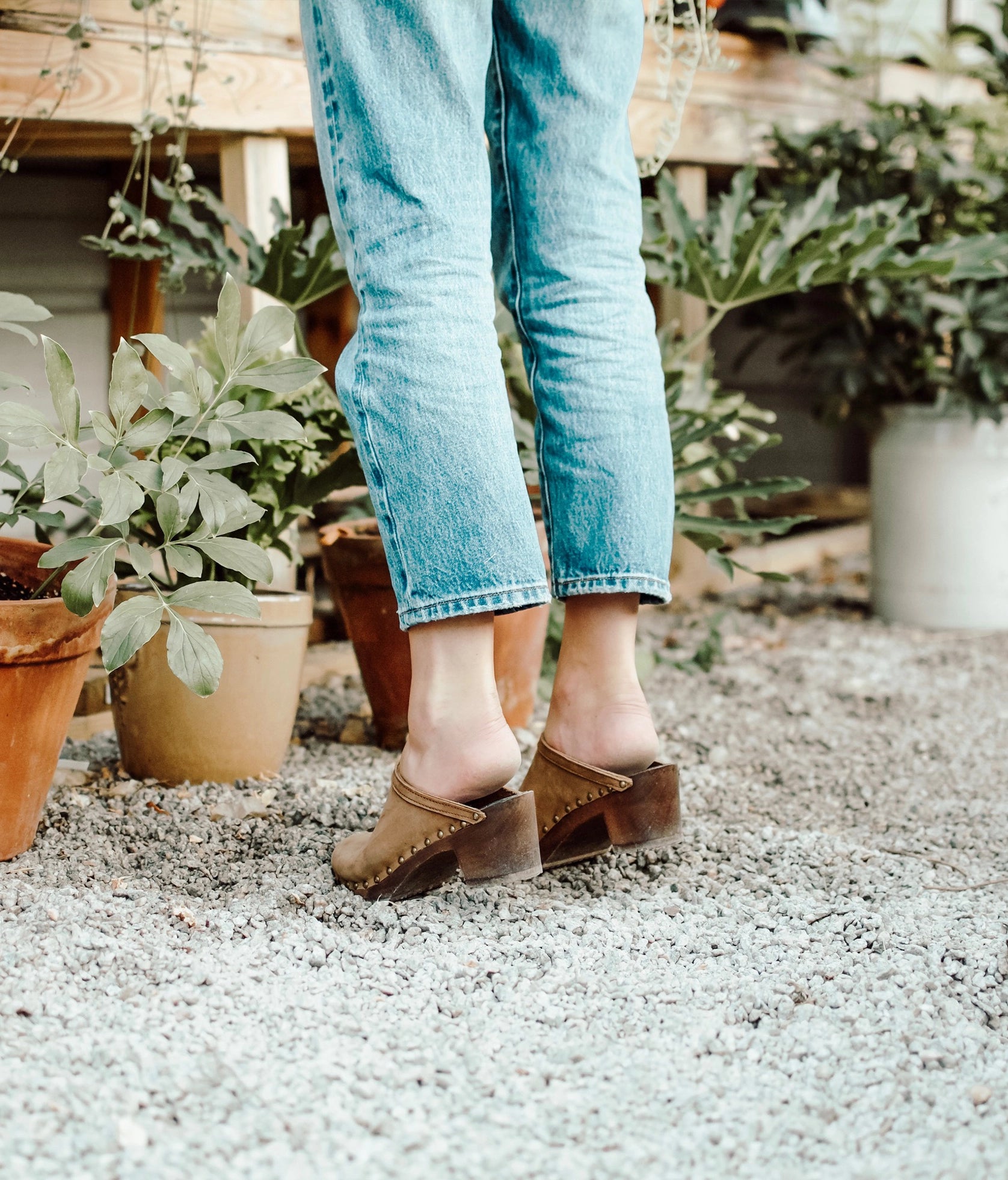high heeled clog mules in light brown nubuck leather stapled on a dark wooden base with brass gold studs