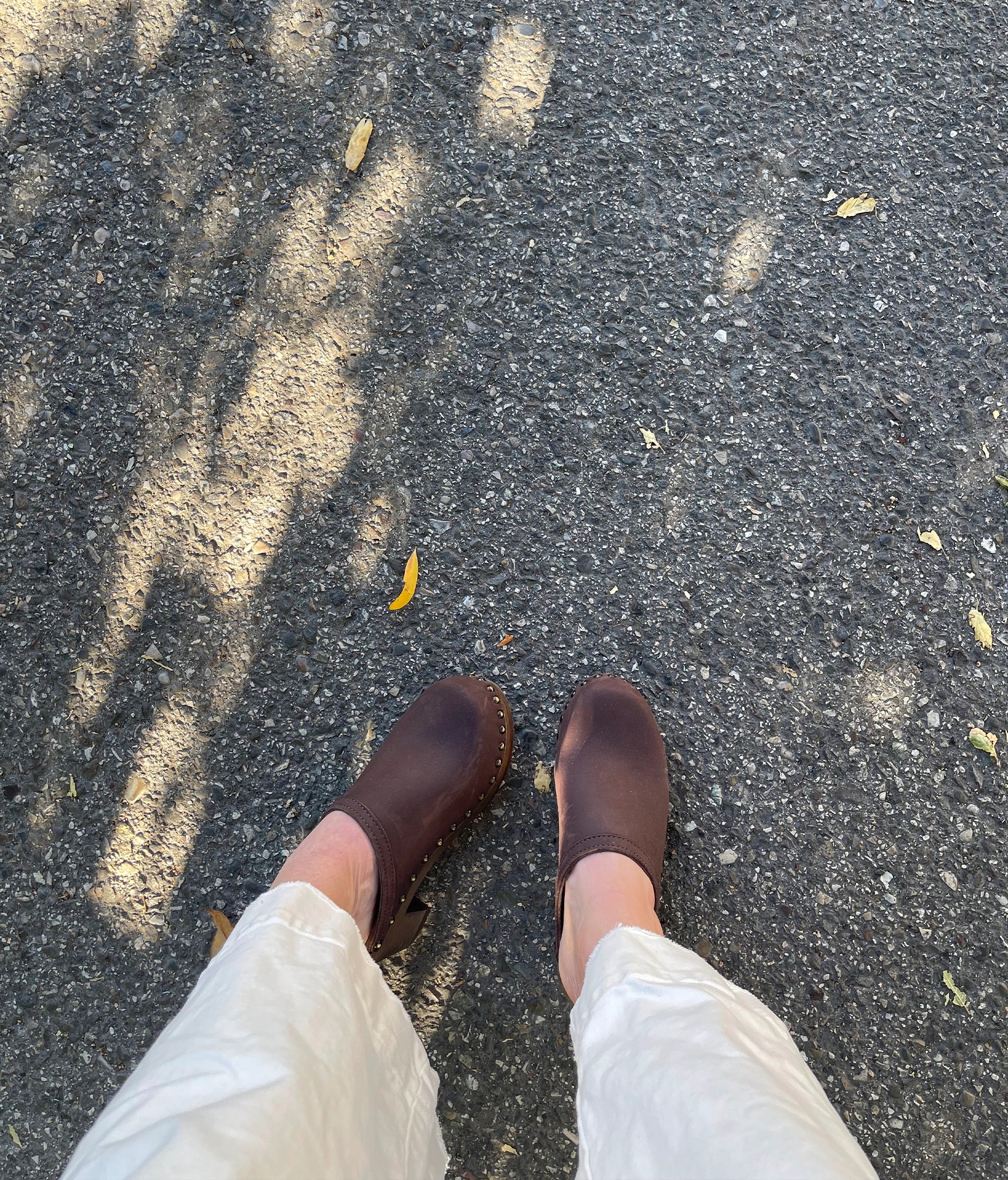 high heeled clog mules in dark brown nubuck leather stapled on a dark wooden base with brass gold studs