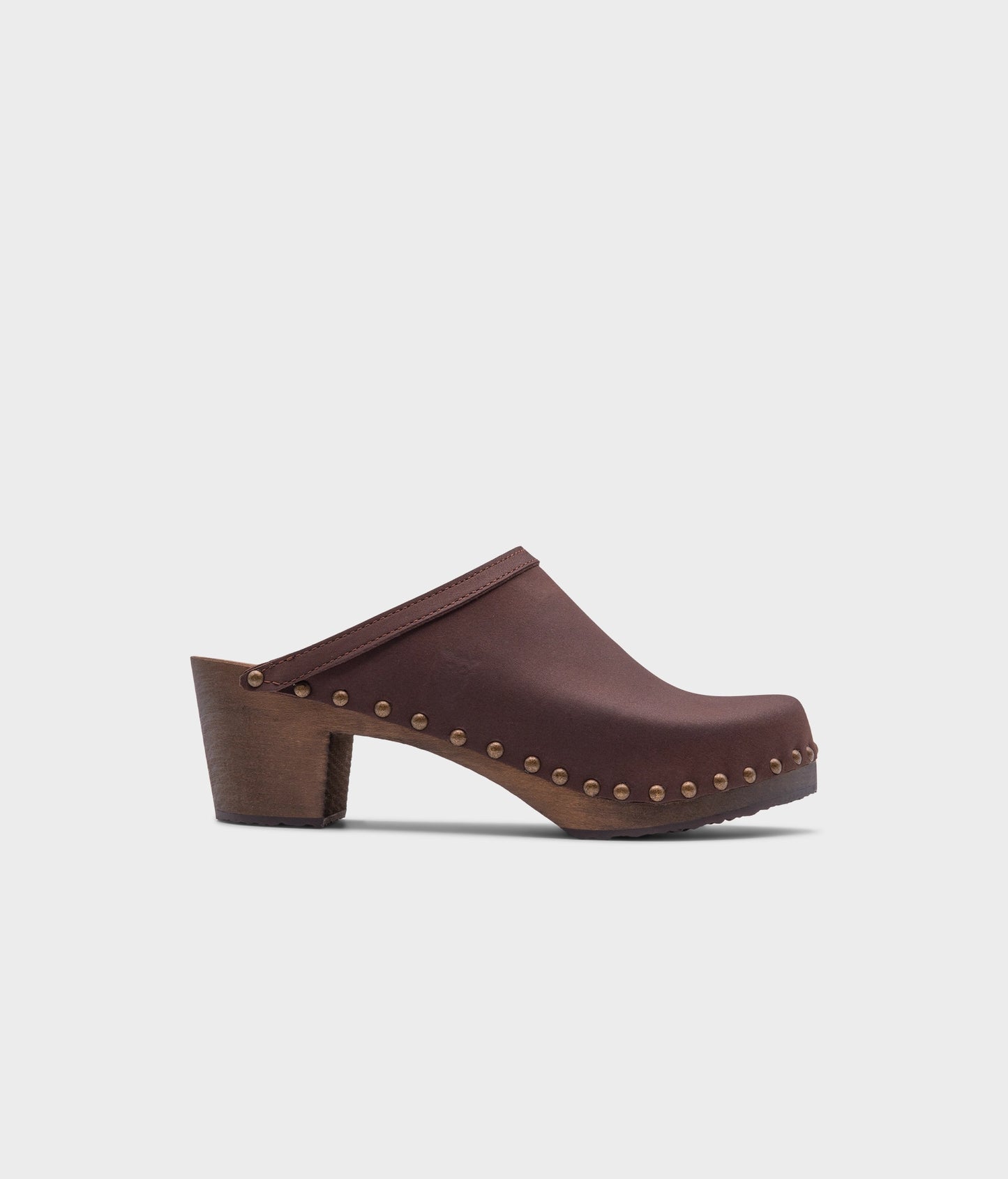 high heeled clog mules in dark brown nubuck leather stapled on a dark wooden base with brass gold studs