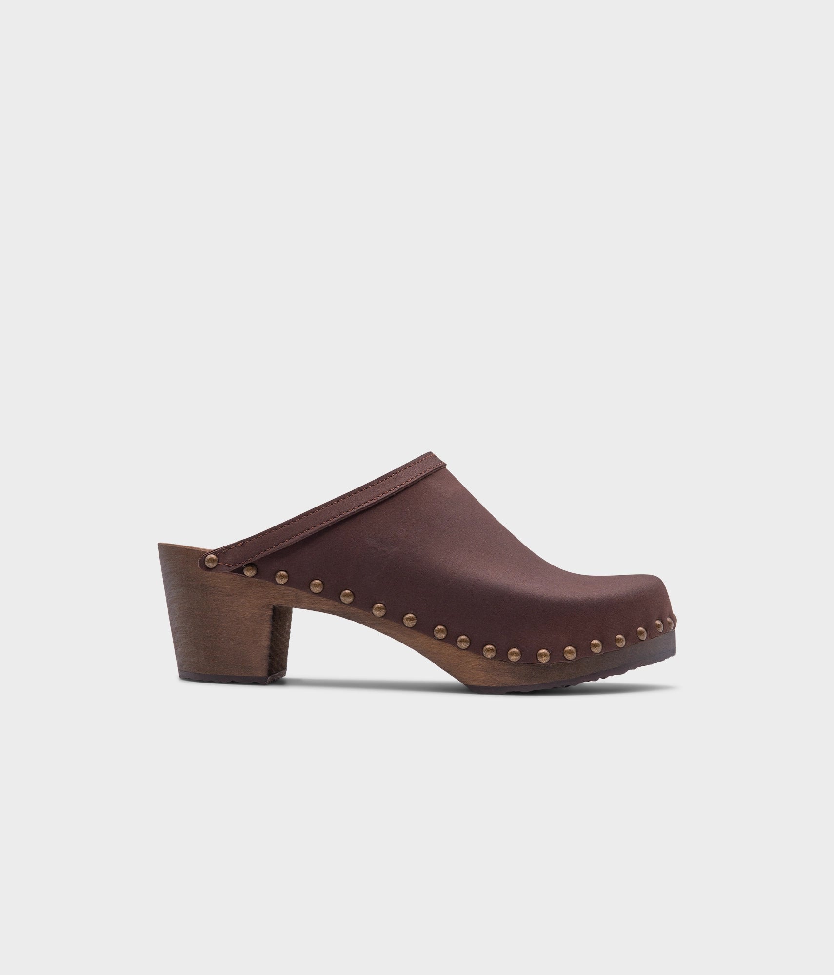 high heeled clog mules in dark brown nubuck leather stapled on a dark wooden base with brass gold studs