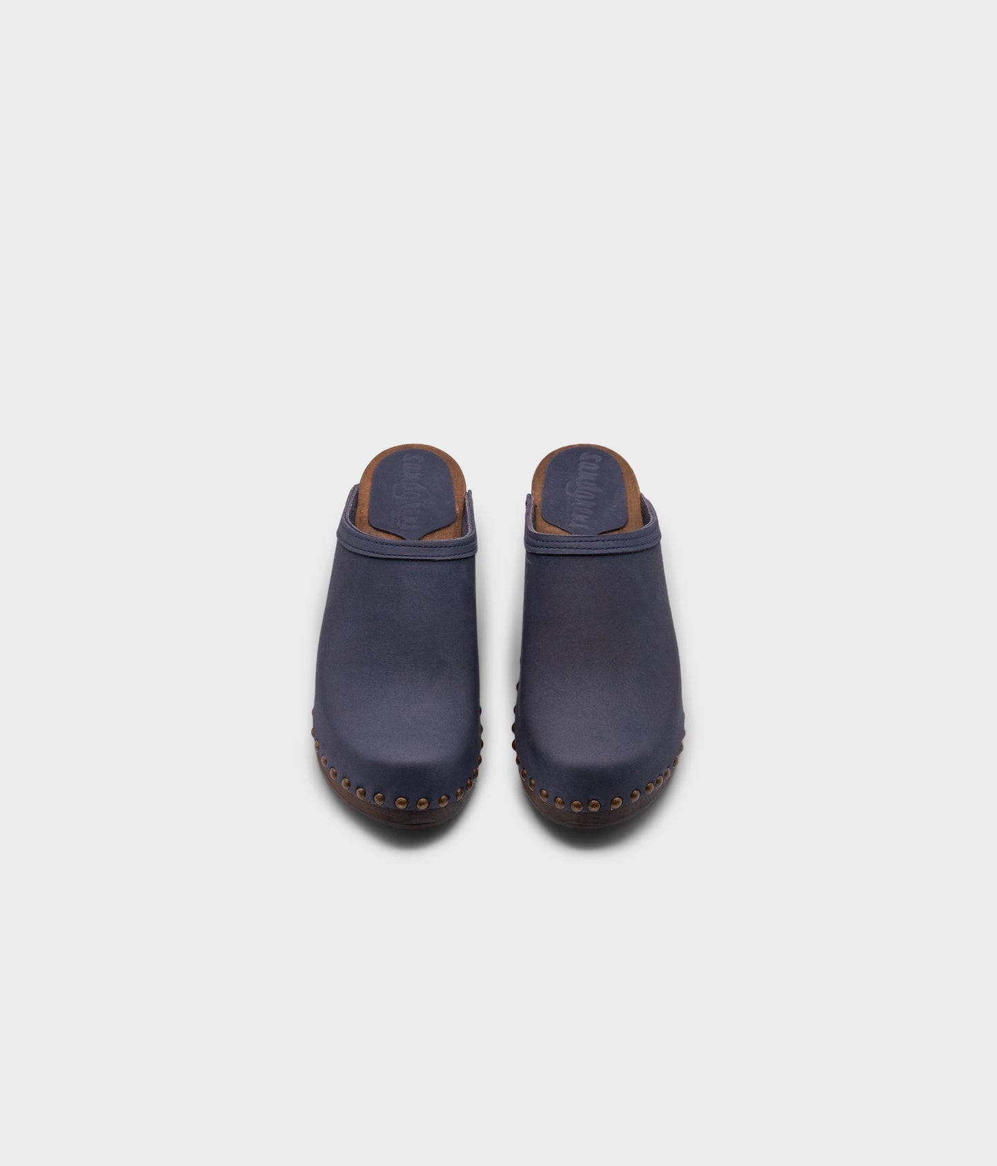 high heeled clog mules in navy blue nubuck leather stapled on a dark wooden base with brass gold studs
