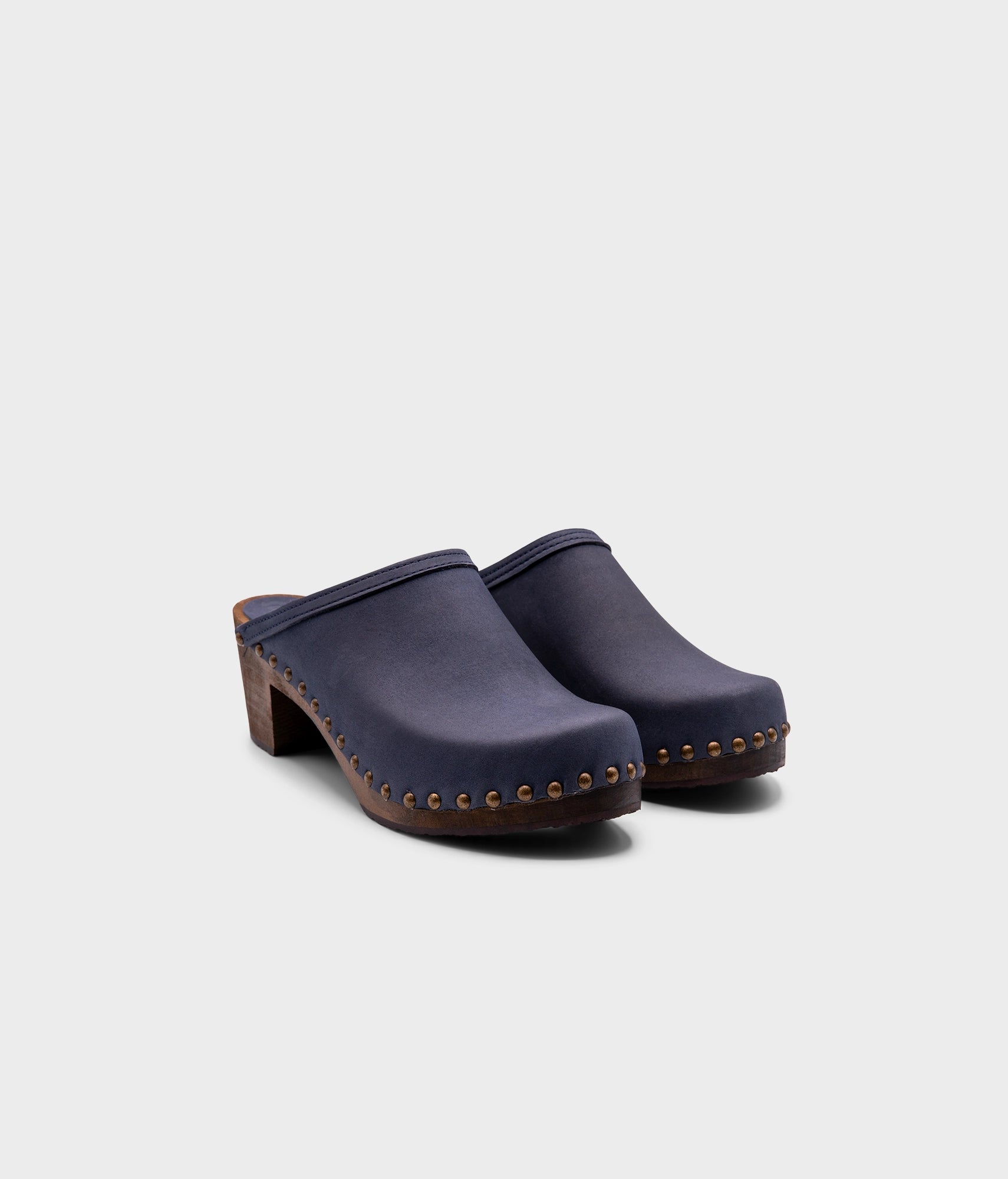 high heeled clog mules in navy blue nubuck leather stapled on a dark wooden base with brass gold studs