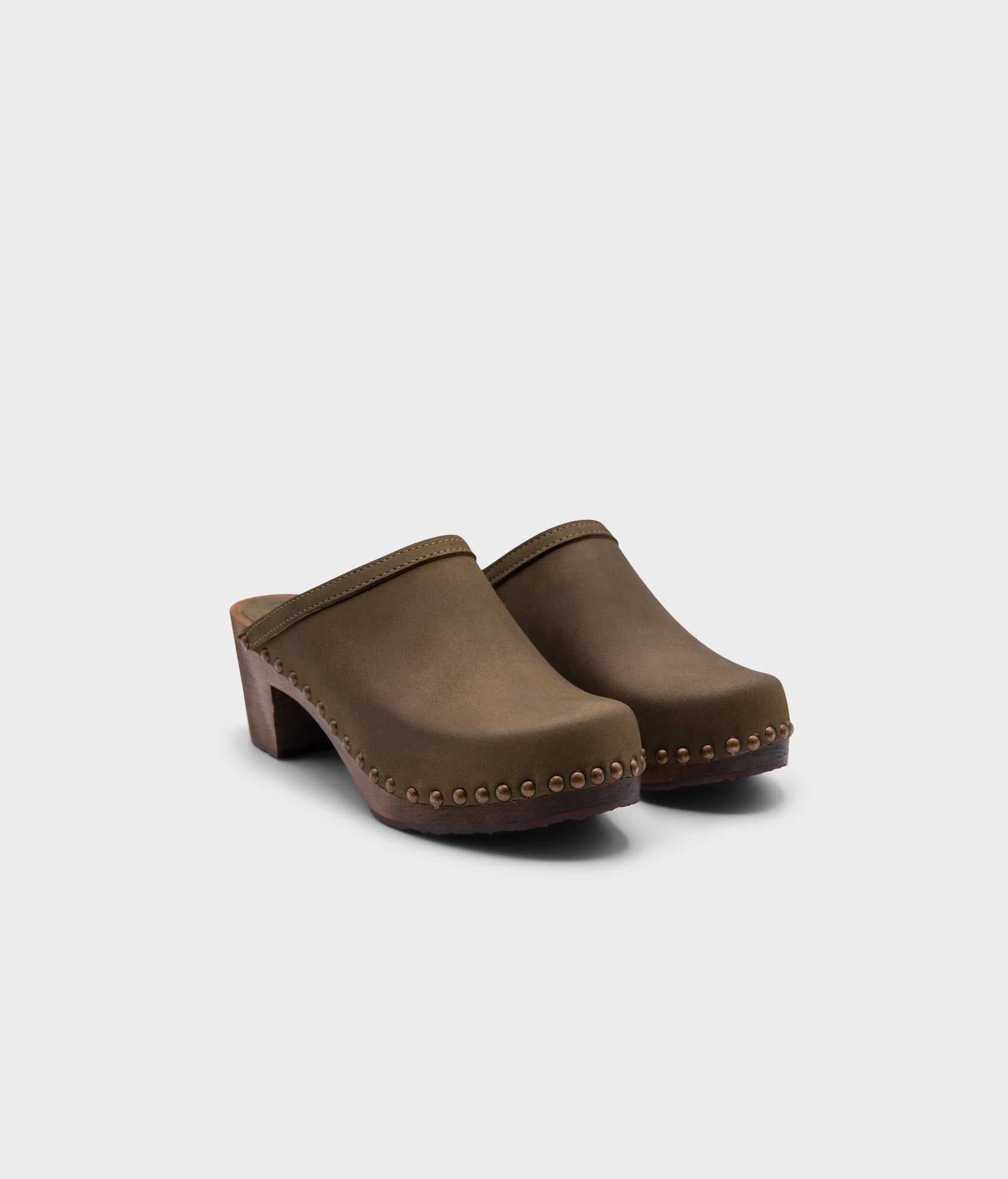 high heeled clog mules in olive green nubuck leather stapled on a dark wooden base with brass gold studs